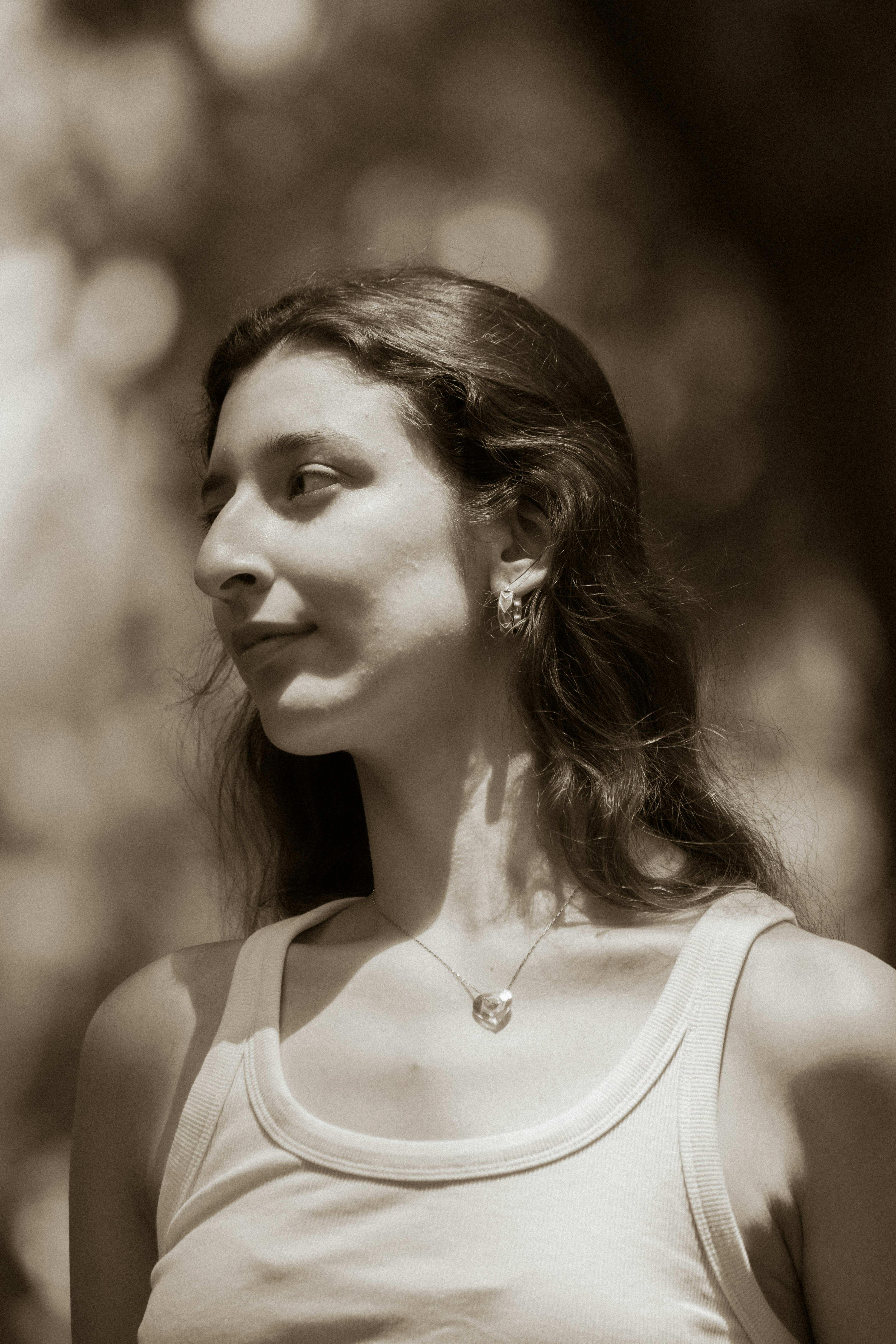 Young woman in a tank top looking left outdoors