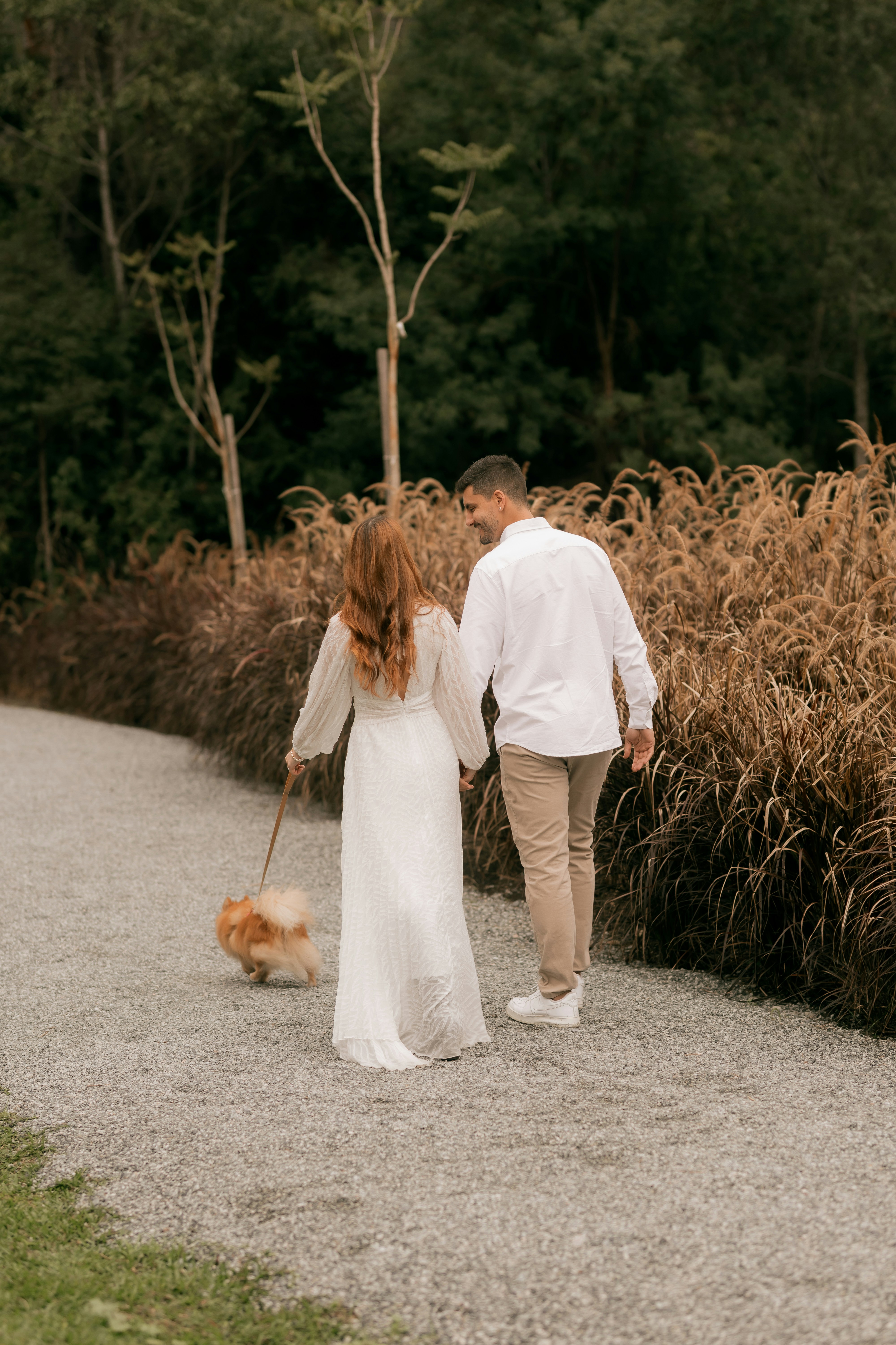 Couple holding hands walking dog on a park path