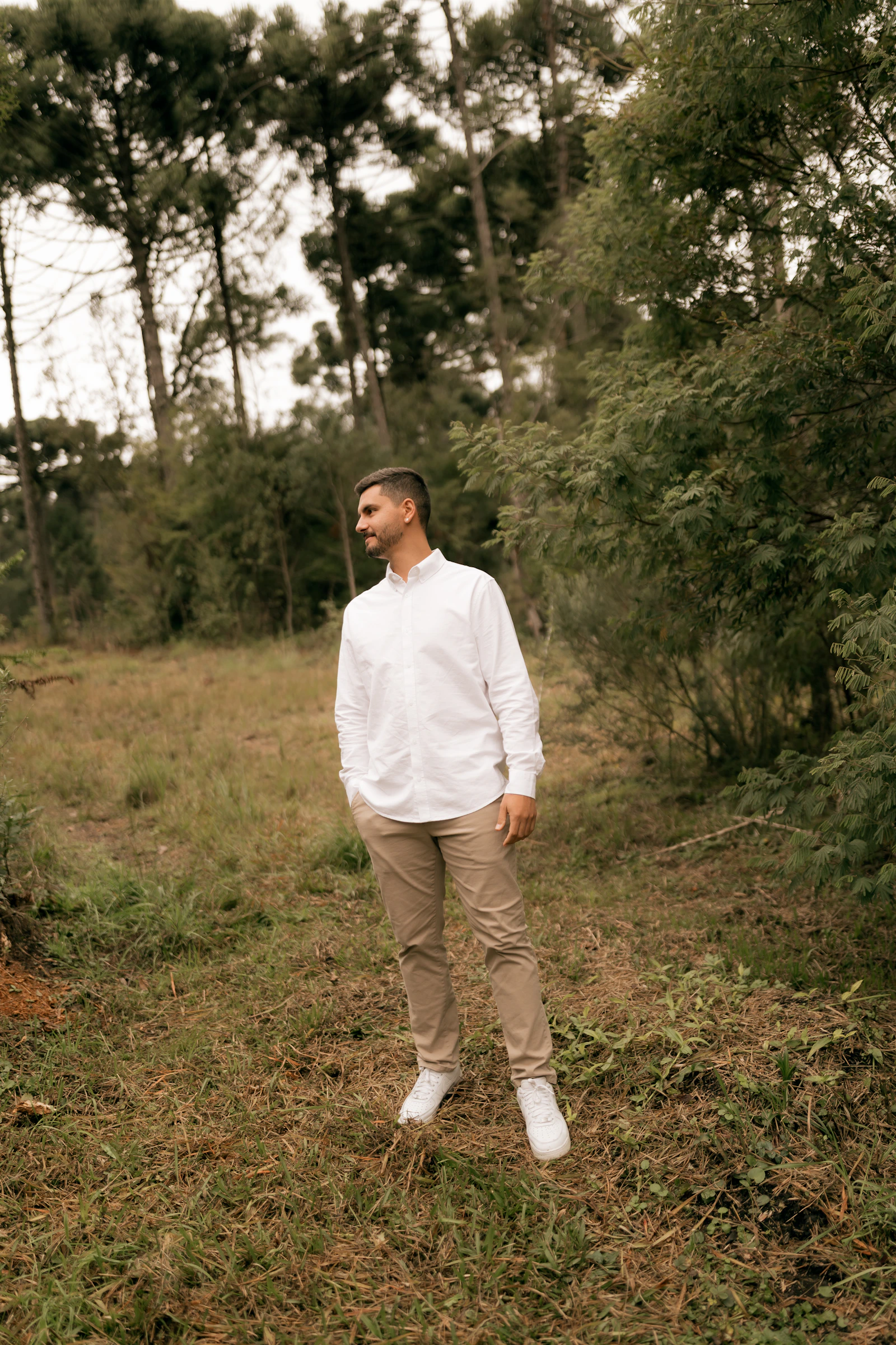 Man in white shirt and khaki chinos in forest clearing