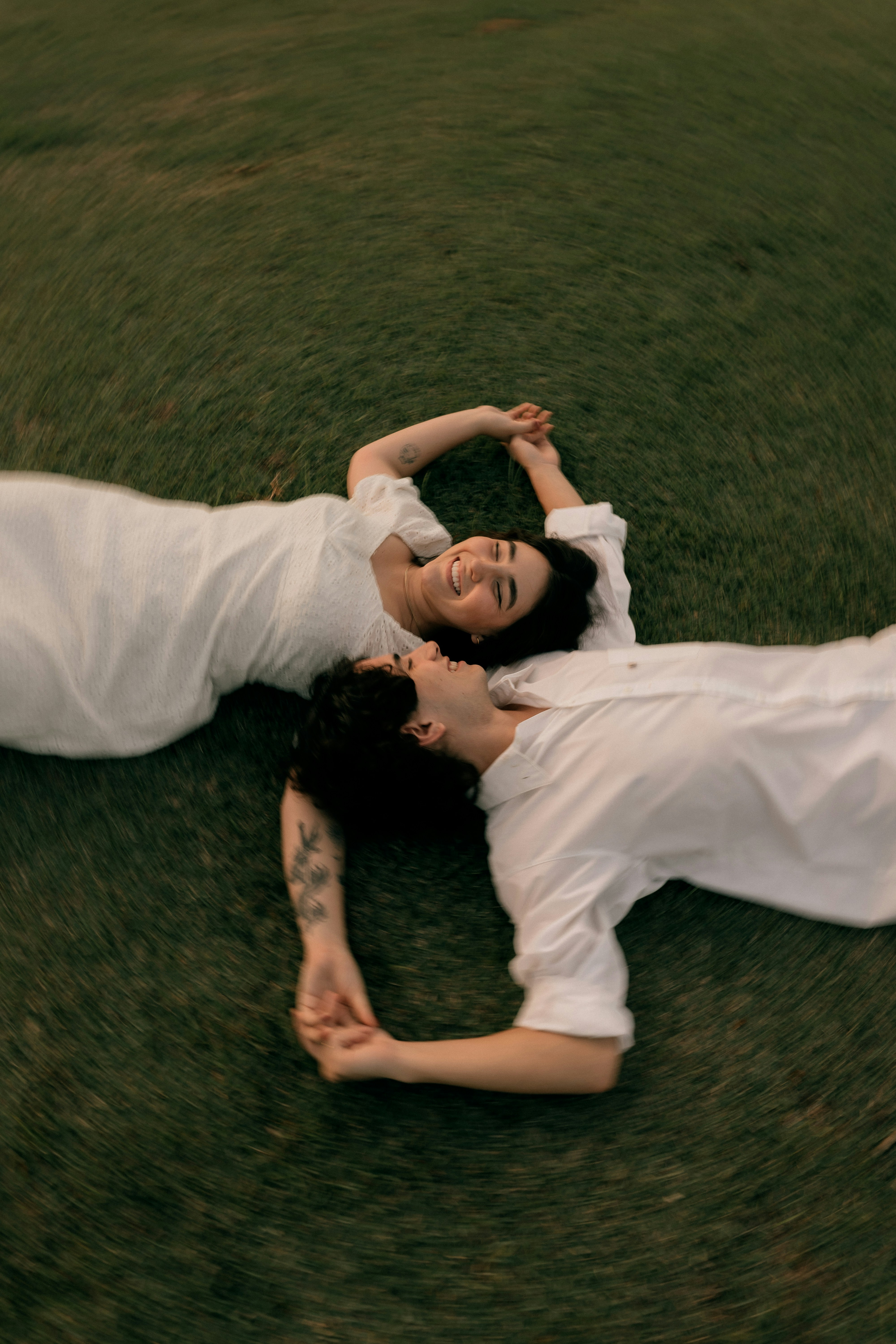Two happy people in white lying on green grass.