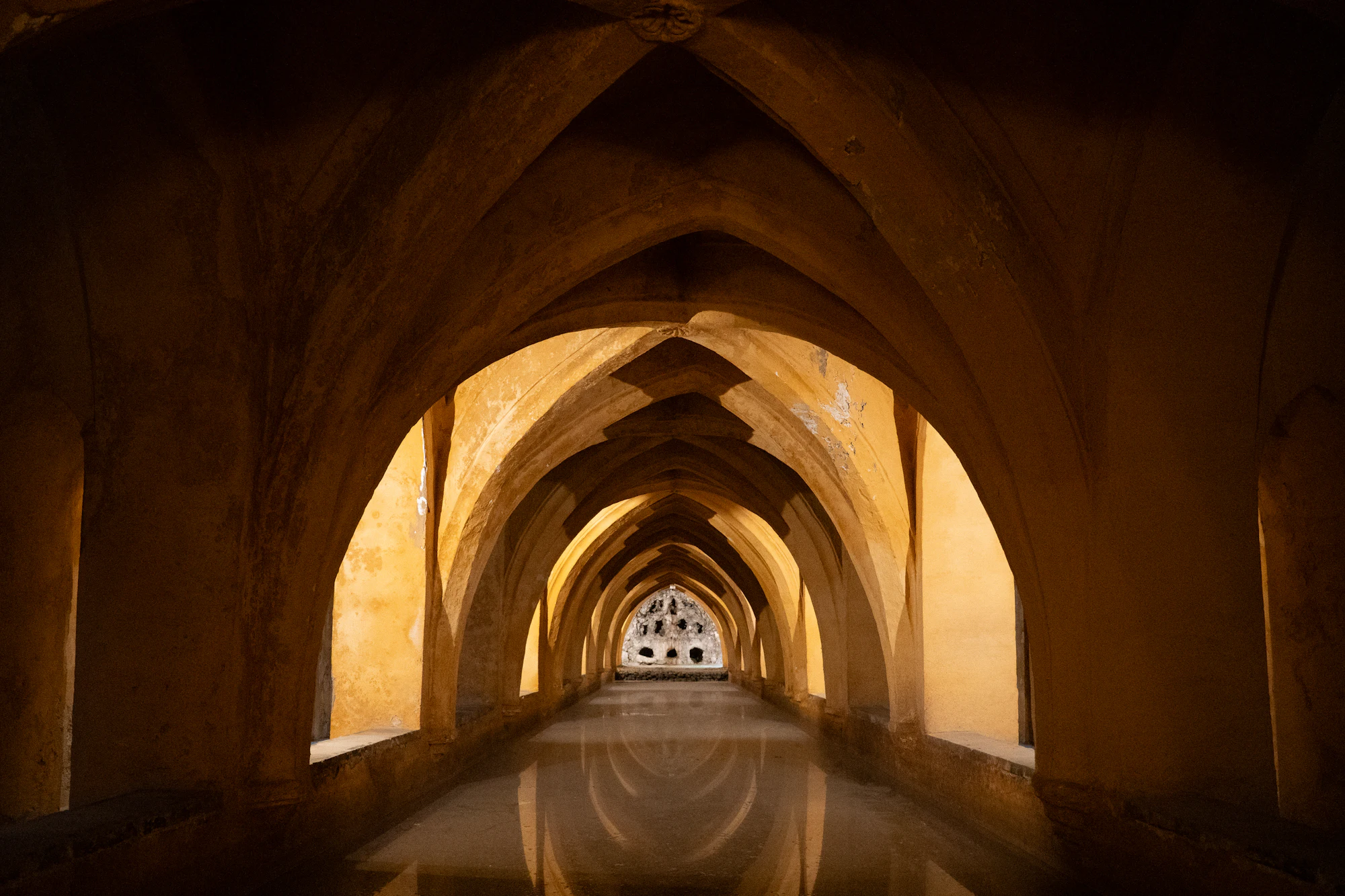 Arched stone hall reflected in still water under warm light