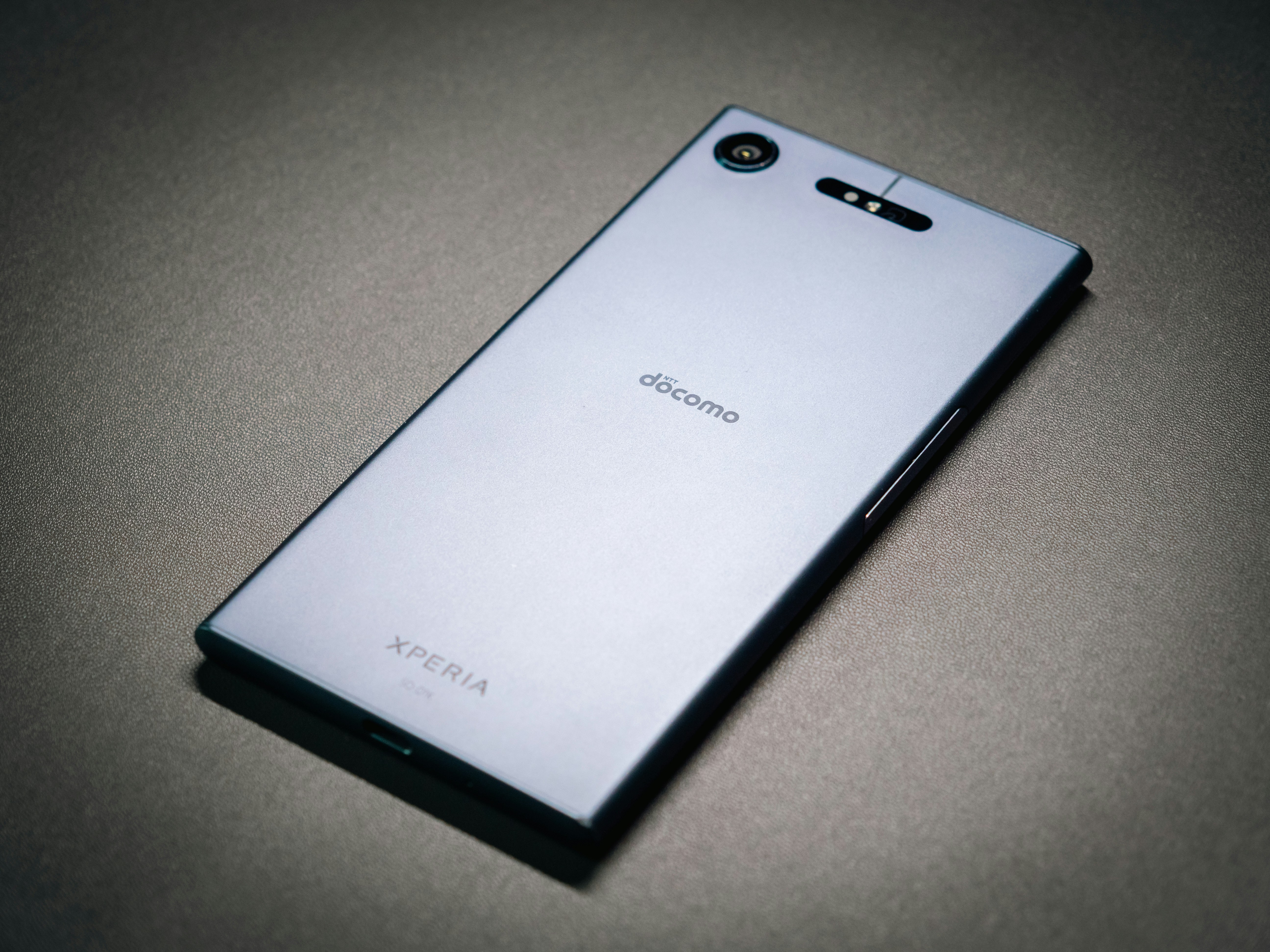 Un smartphone argenté avec la marque « docomo » sur une surface sombre.