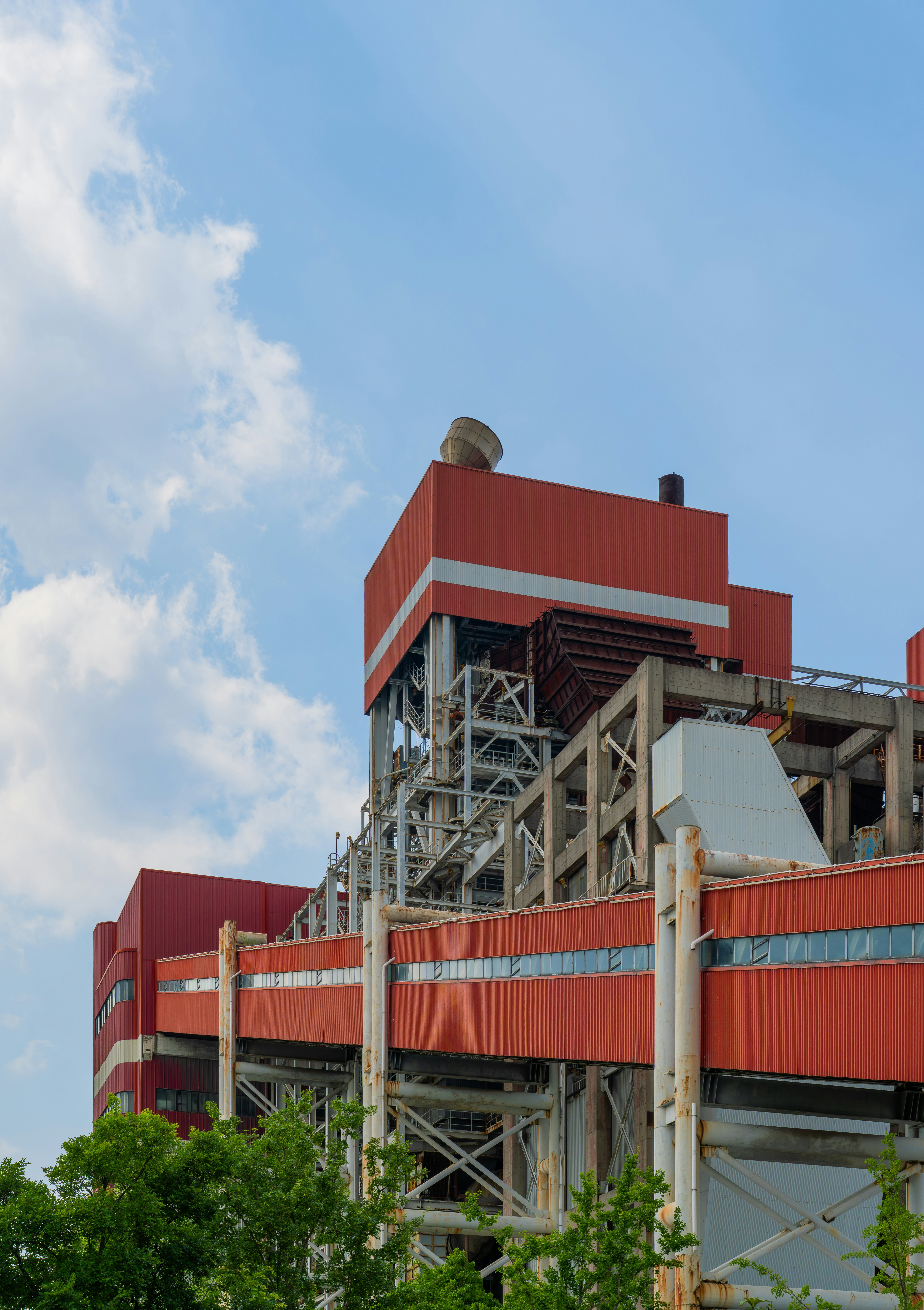 Bâtiment industriel rouge avec une ossature métallique sur un ciel bleu.