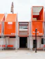 Modern building with orange box structures and scaffolding.