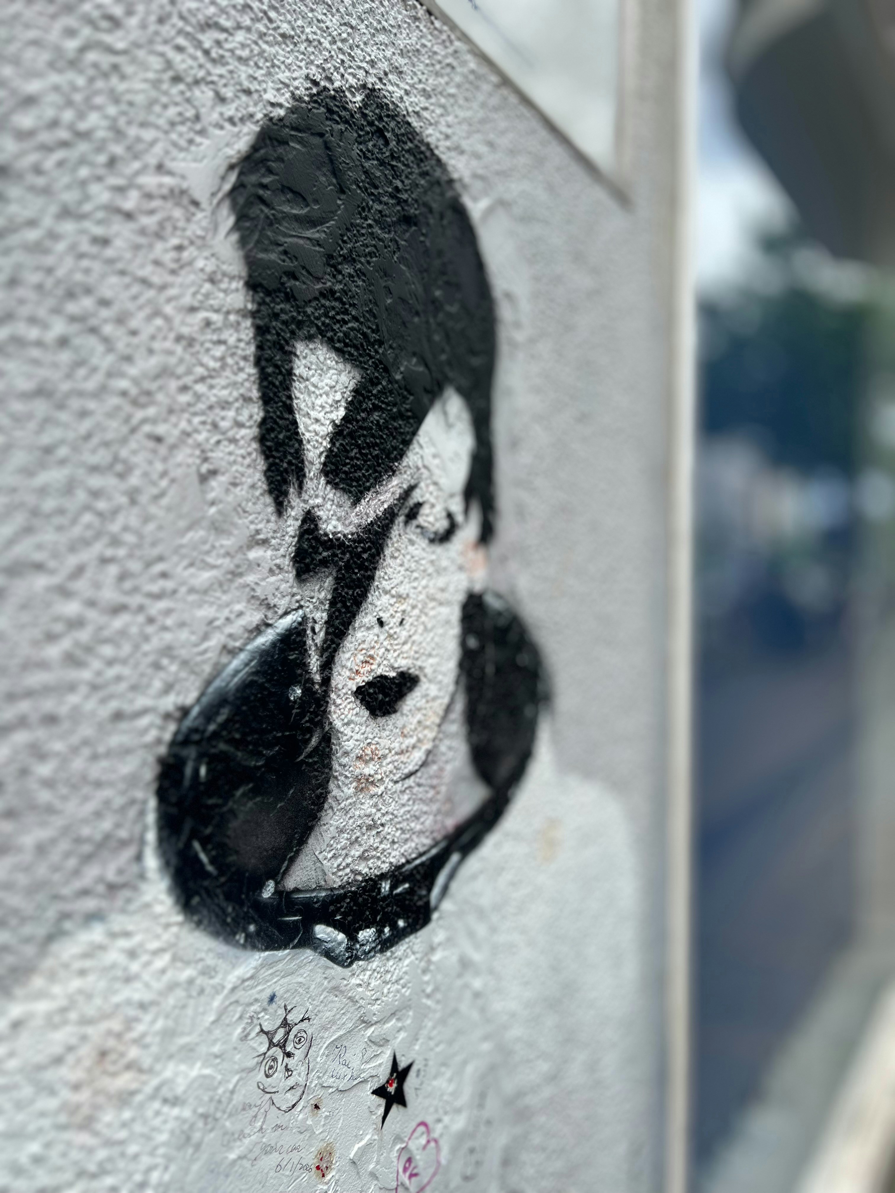 Arte stencil con fulmini di David Bowie su una parete testurizzata.