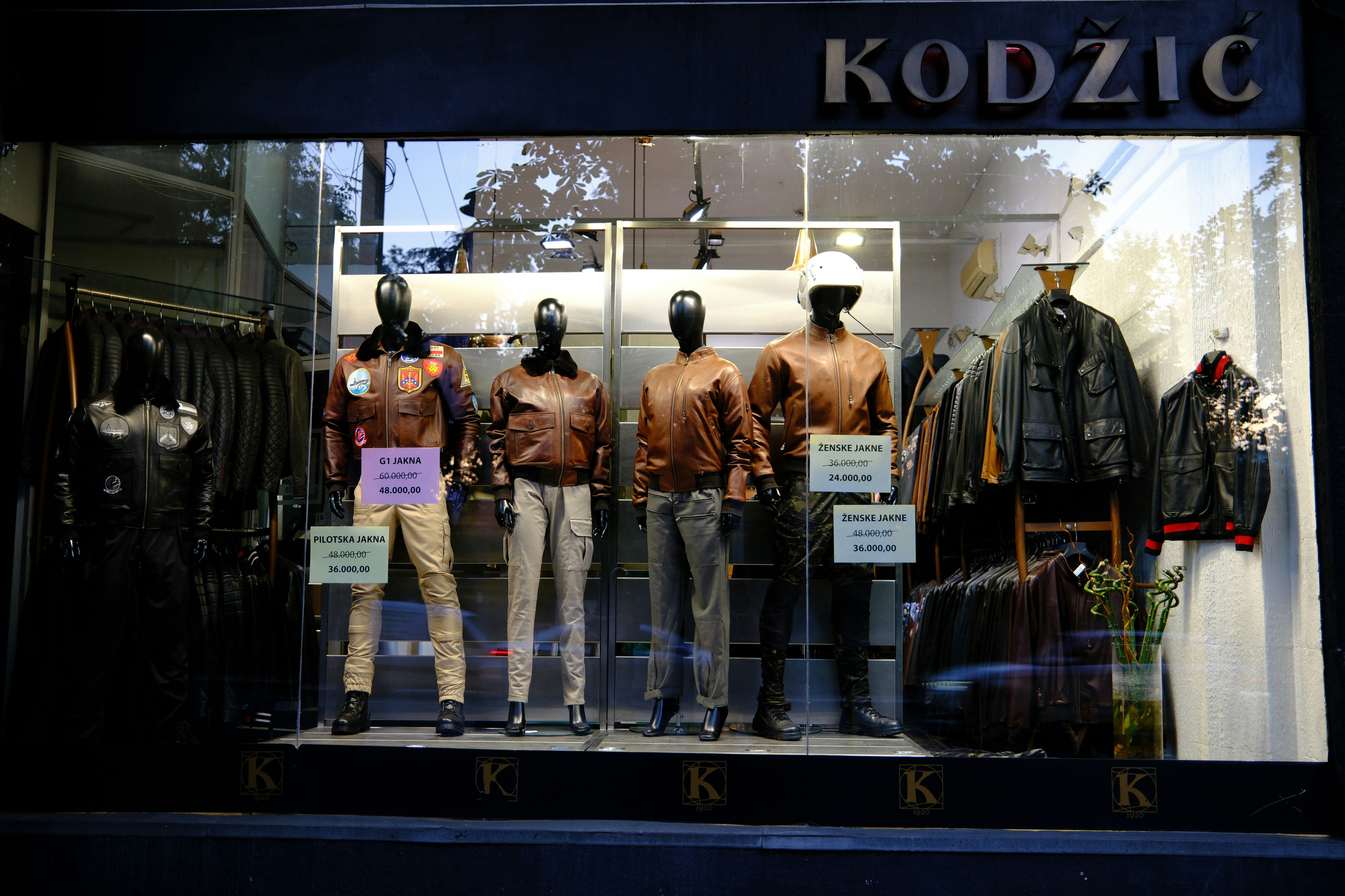 A storefront window displays mannequins wearing leather jackets and clothing