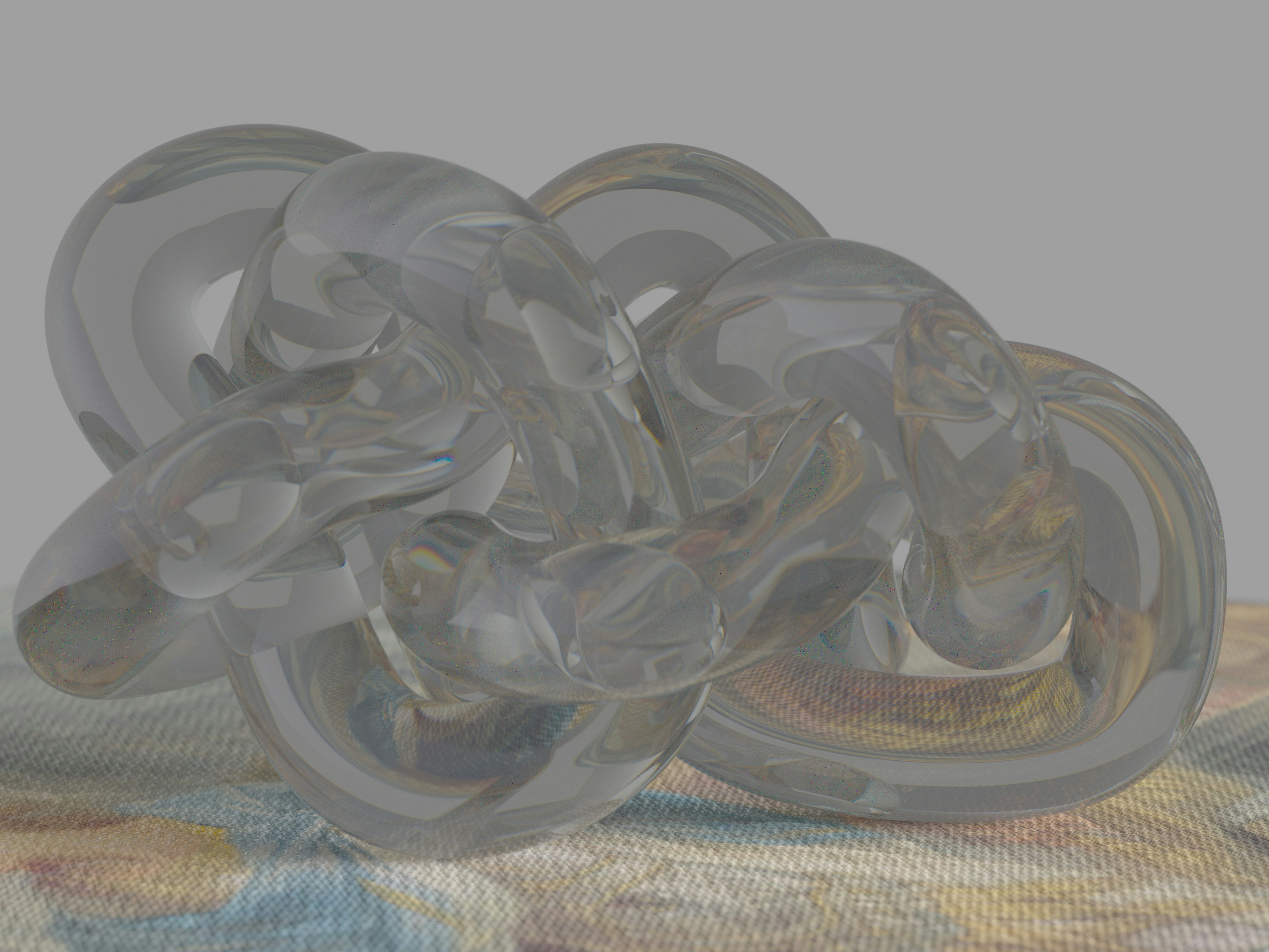 A clear, tangled glass sculpture on a textured surface.