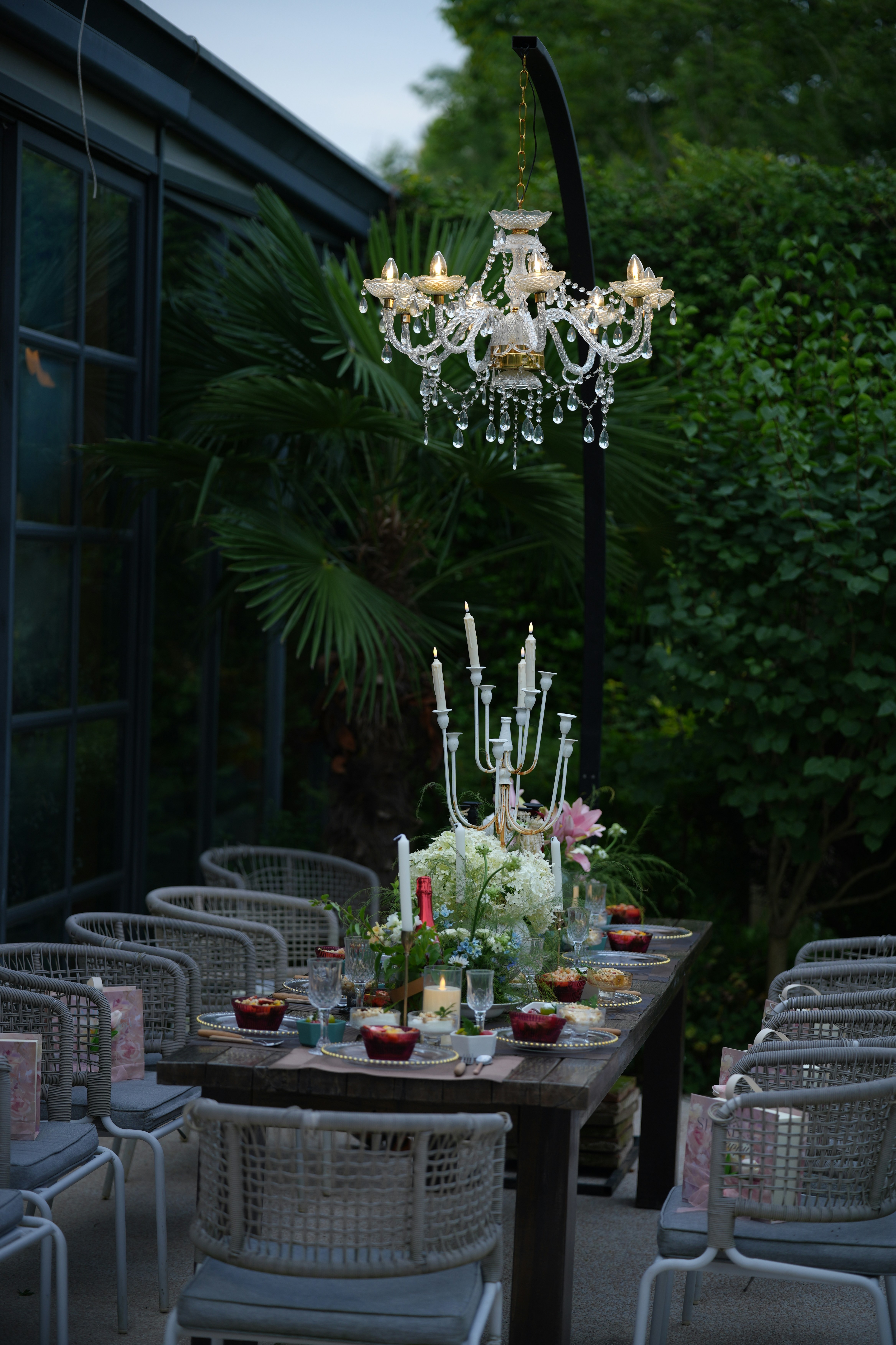 Elegant outdoor dining table set with a chandelier and candles.