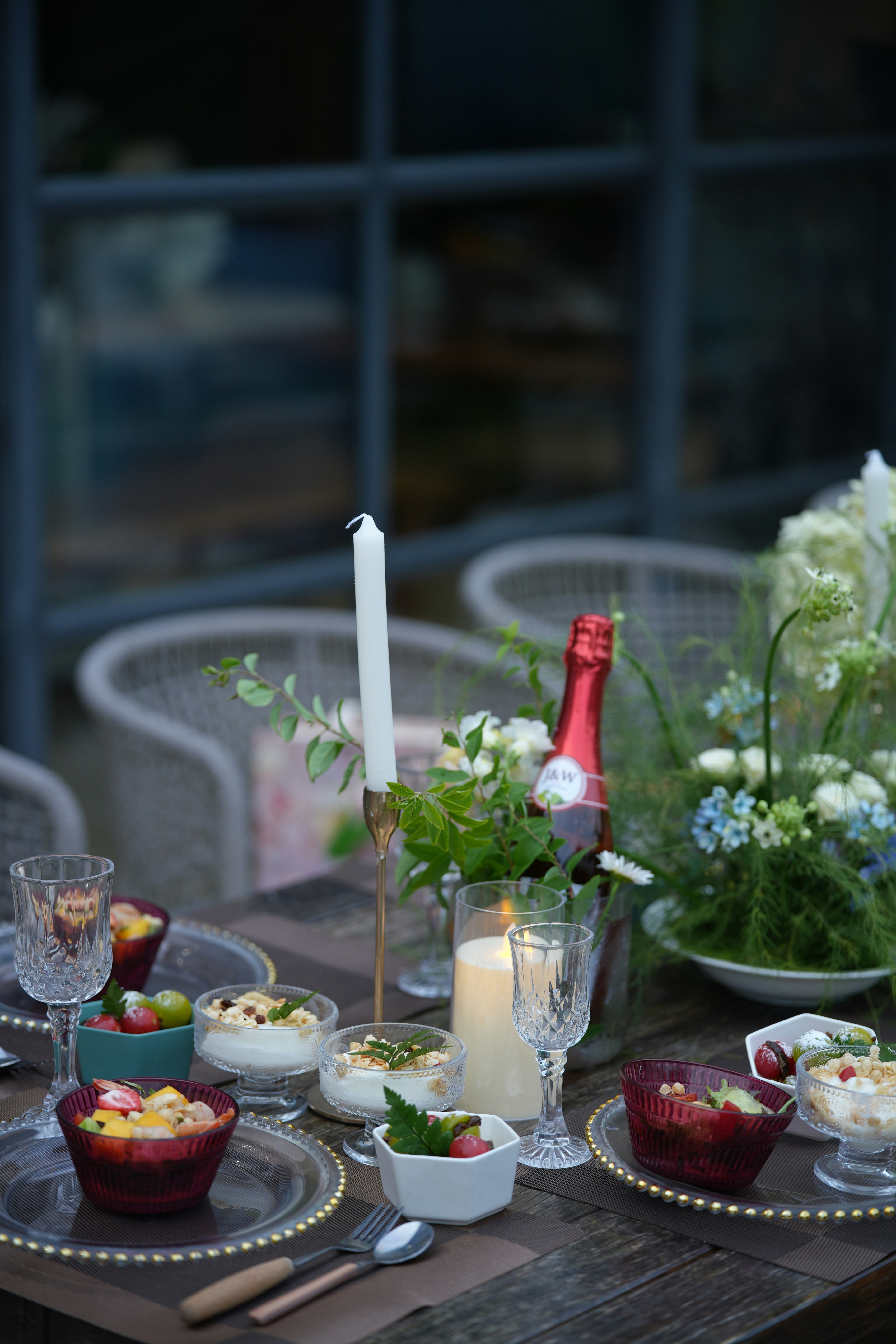 Elegant outdoor table with desserts, candles, and floral arrangements.