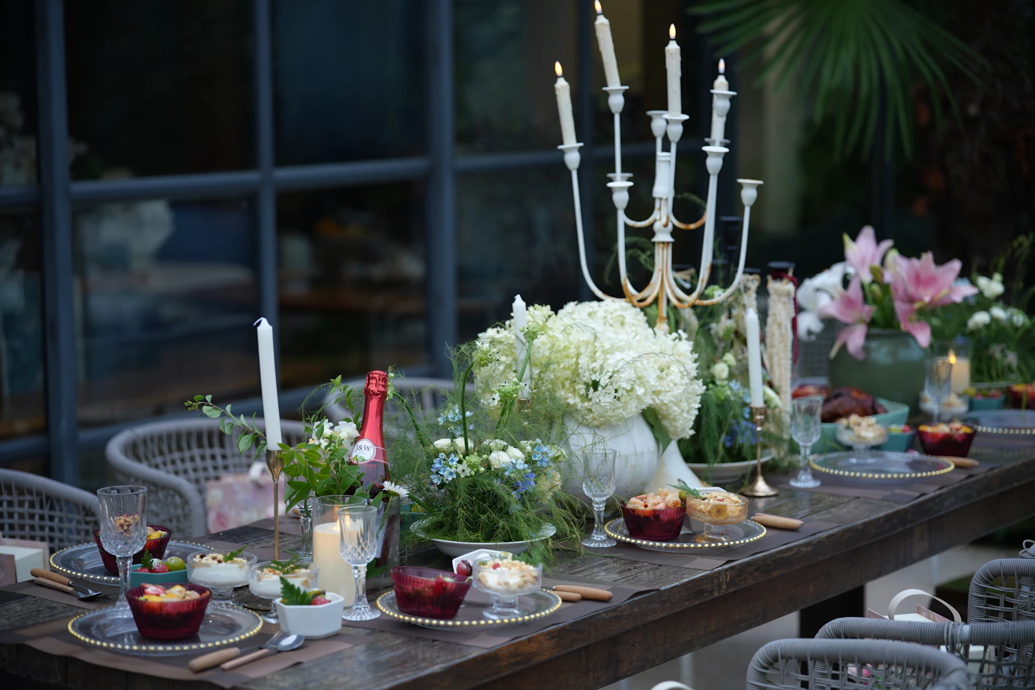 Outdoor dining table prepared with serving pieces, glasses and candles