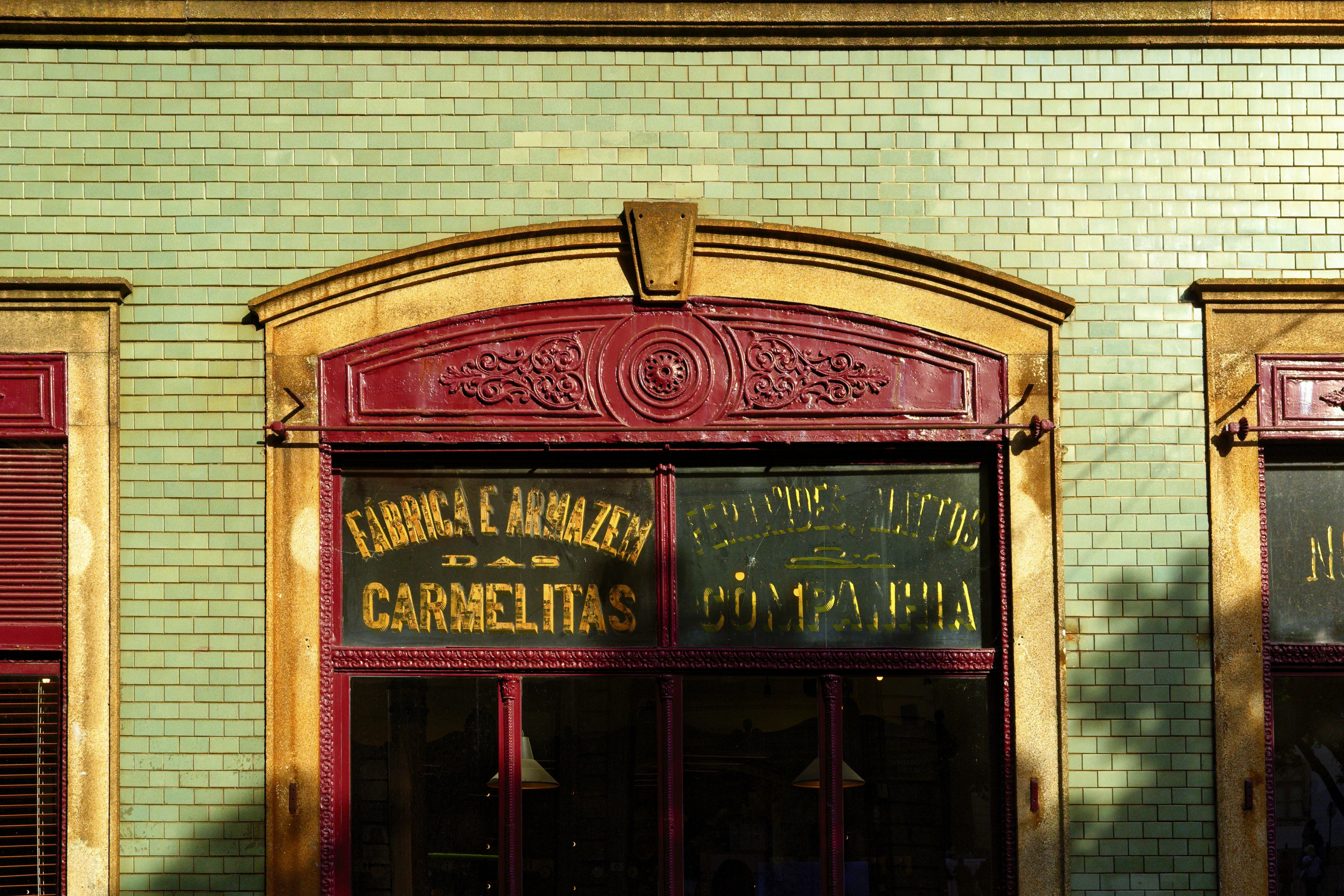 Green brick building with ornate red window and gold lettering.
