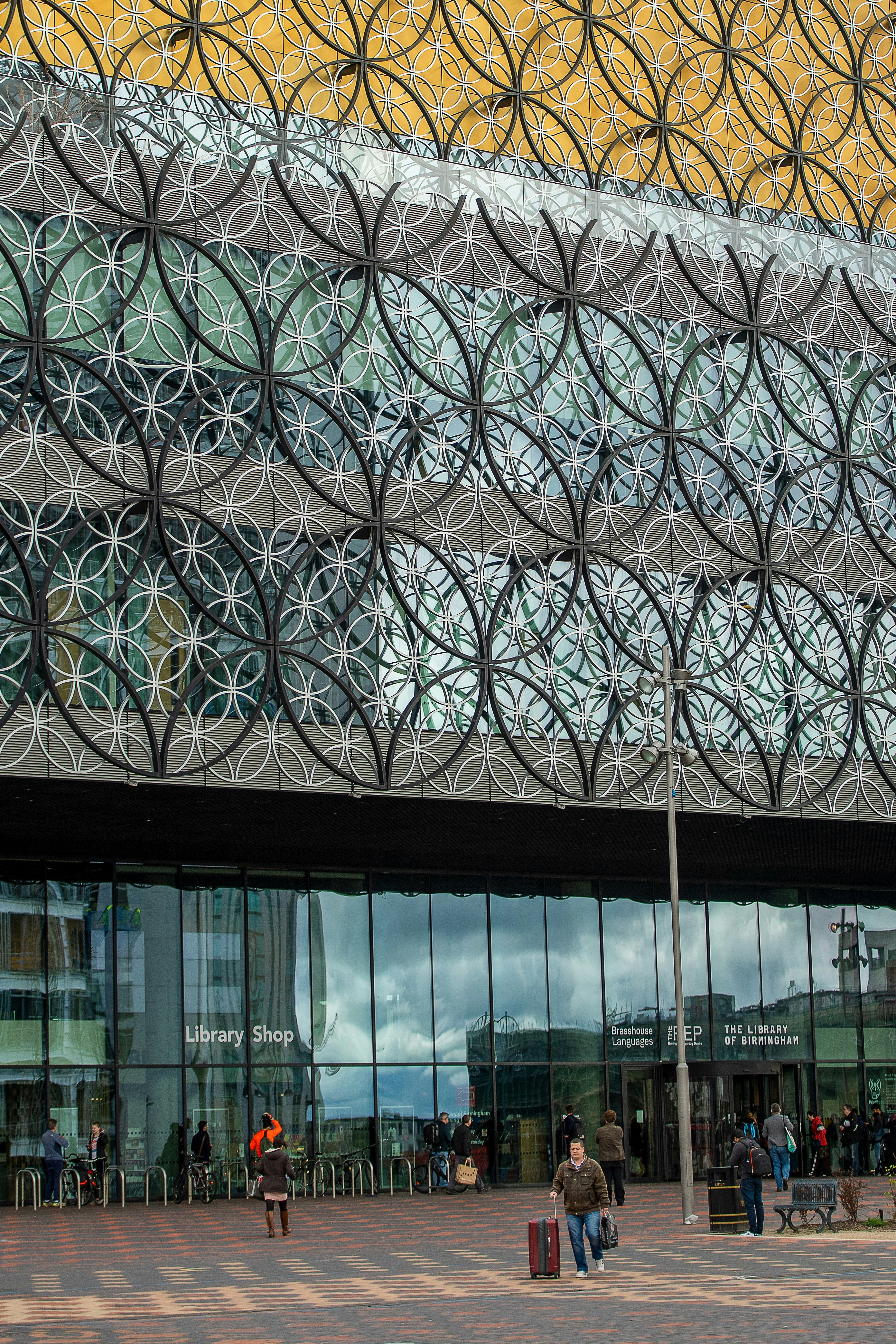 Modern building with intricate circular patterns and people outside.