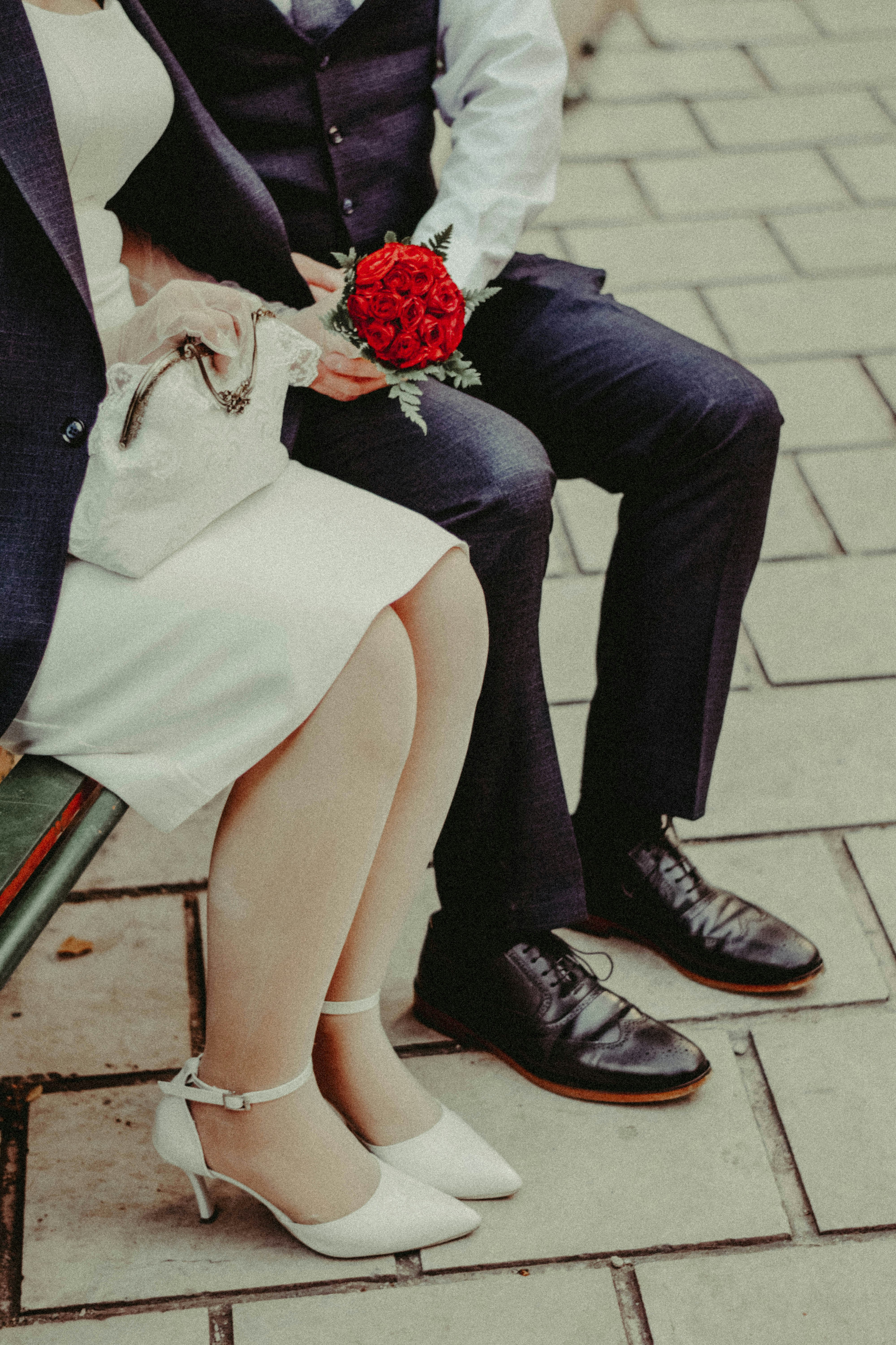 Couple in formal attire holding a vibrant red bouquet