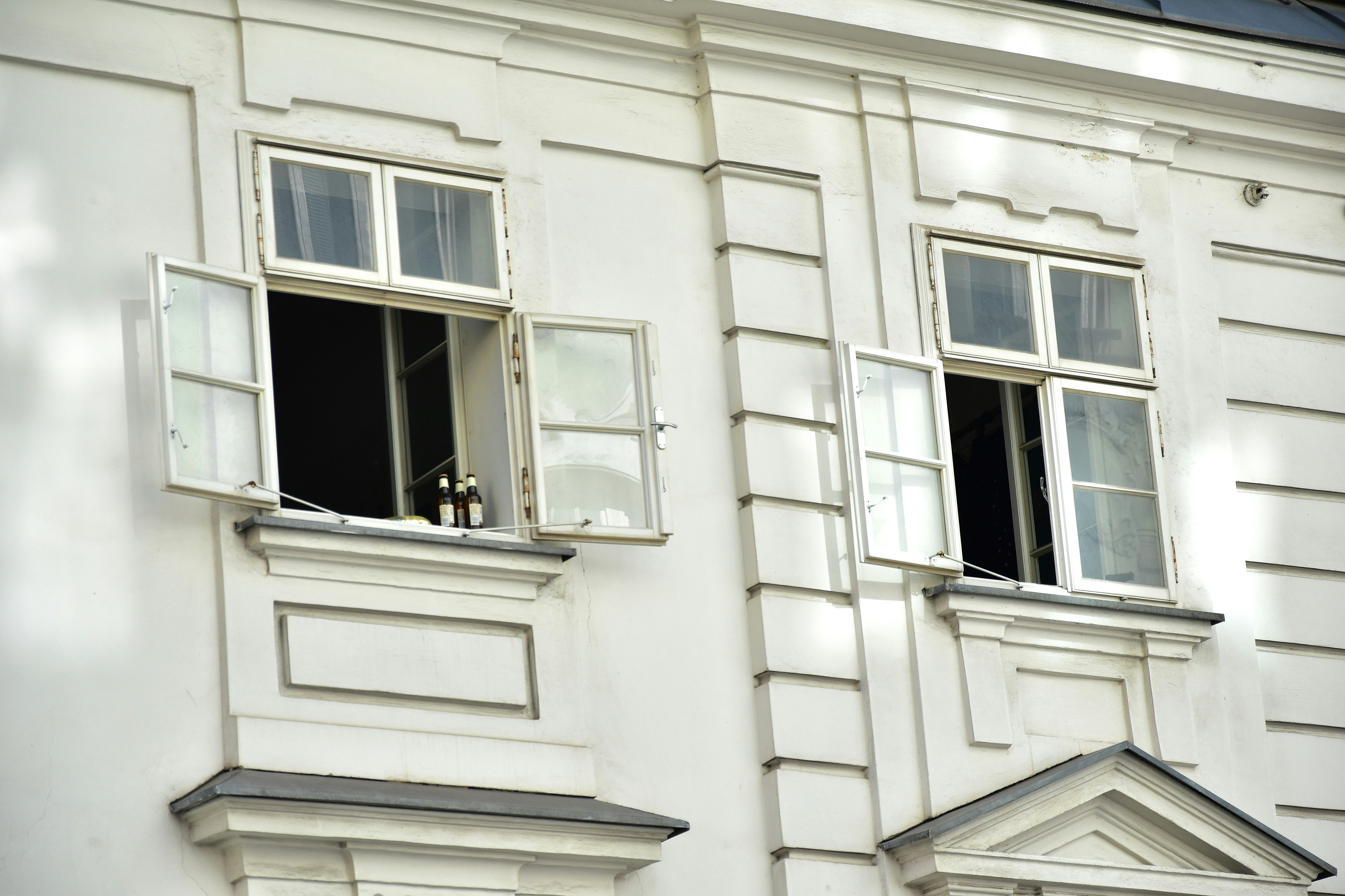 Two open windows on a white building facade