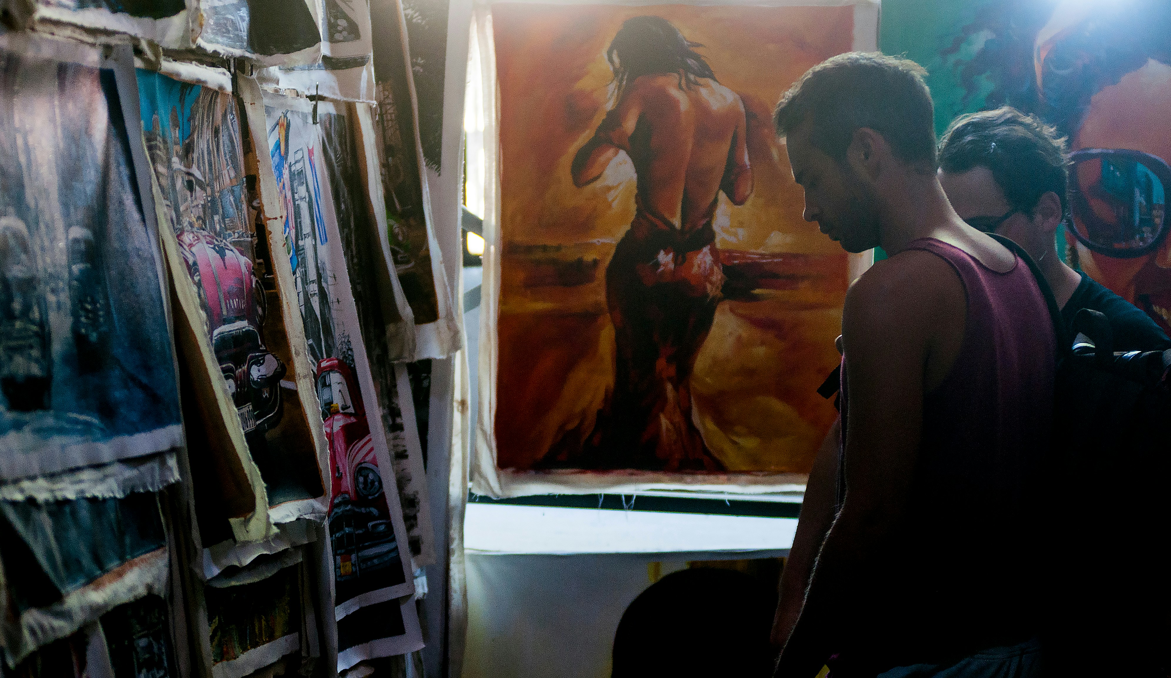A man looks at a painting of a person's back.