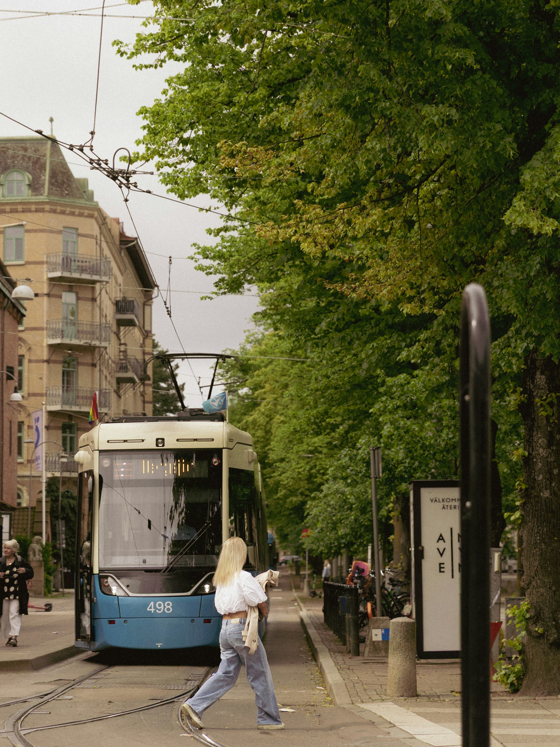 Tranvía azul en una calle de la ciudad con una persona cruzando.