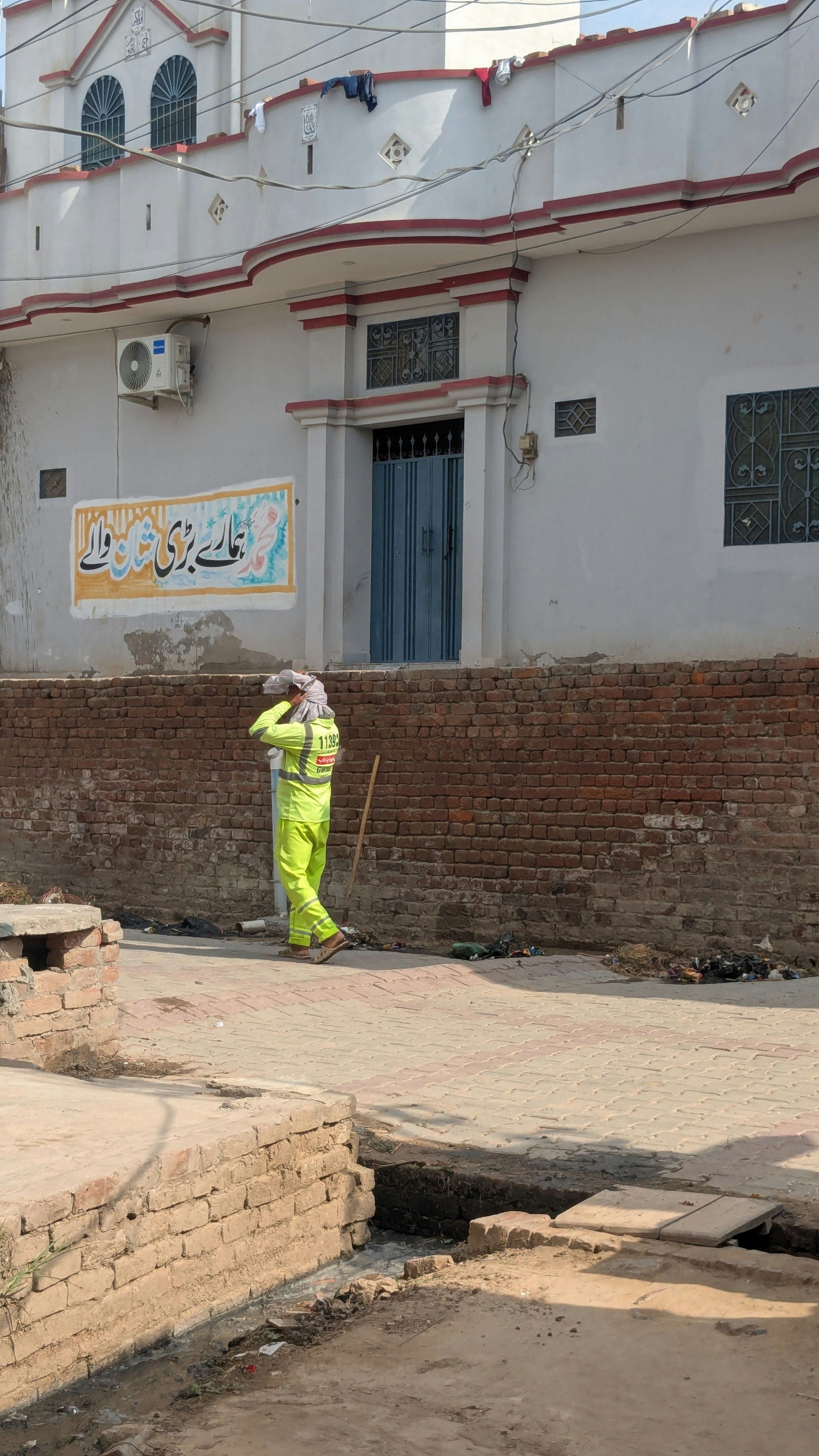 Person in bright yellow uniform walks past a building.