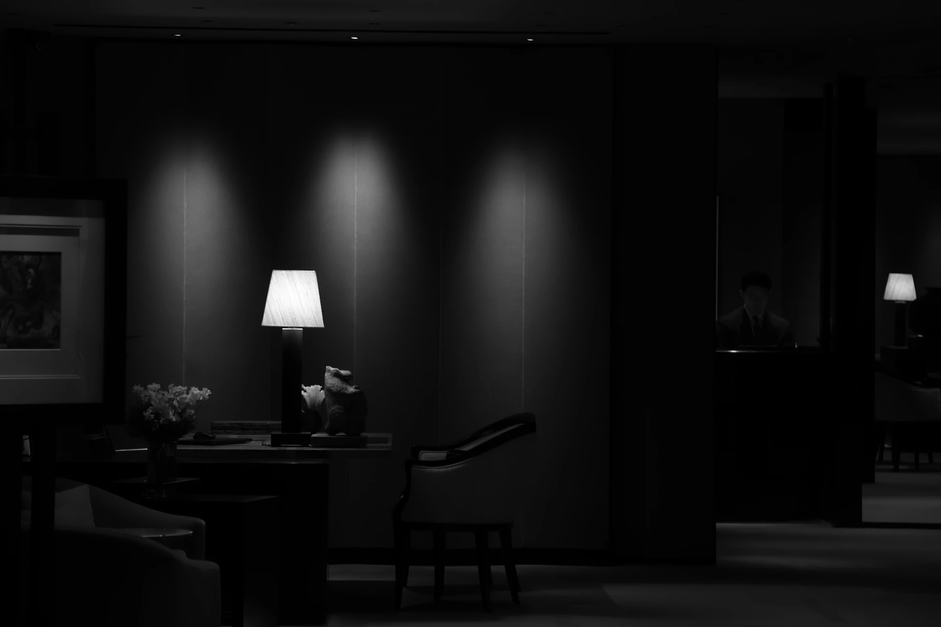 Dark interior featuring a lit table lamp and wall spotlights.