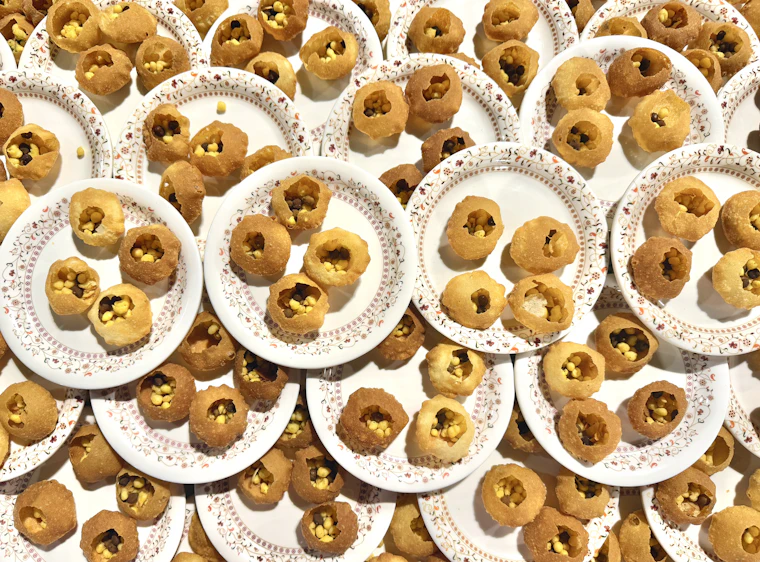 Crisp pani puris lined up on paper plates