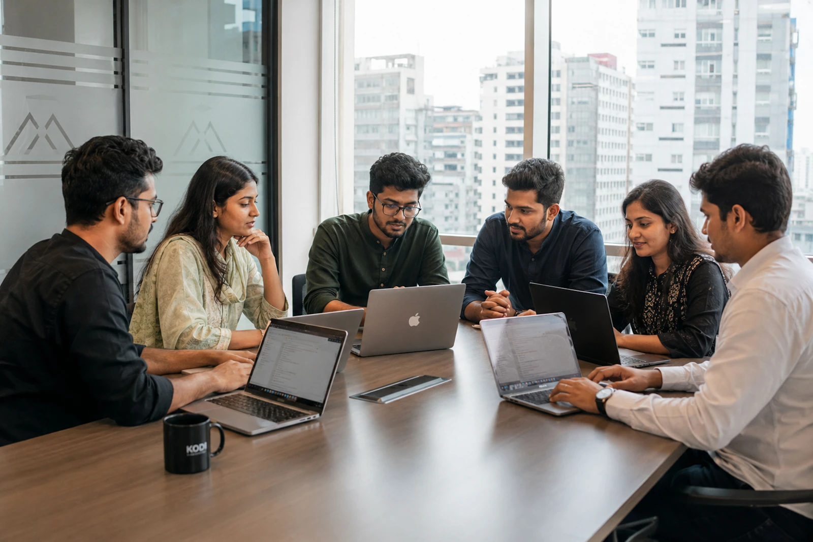 An Indian leadership team in a working session in a modern glass-walled office