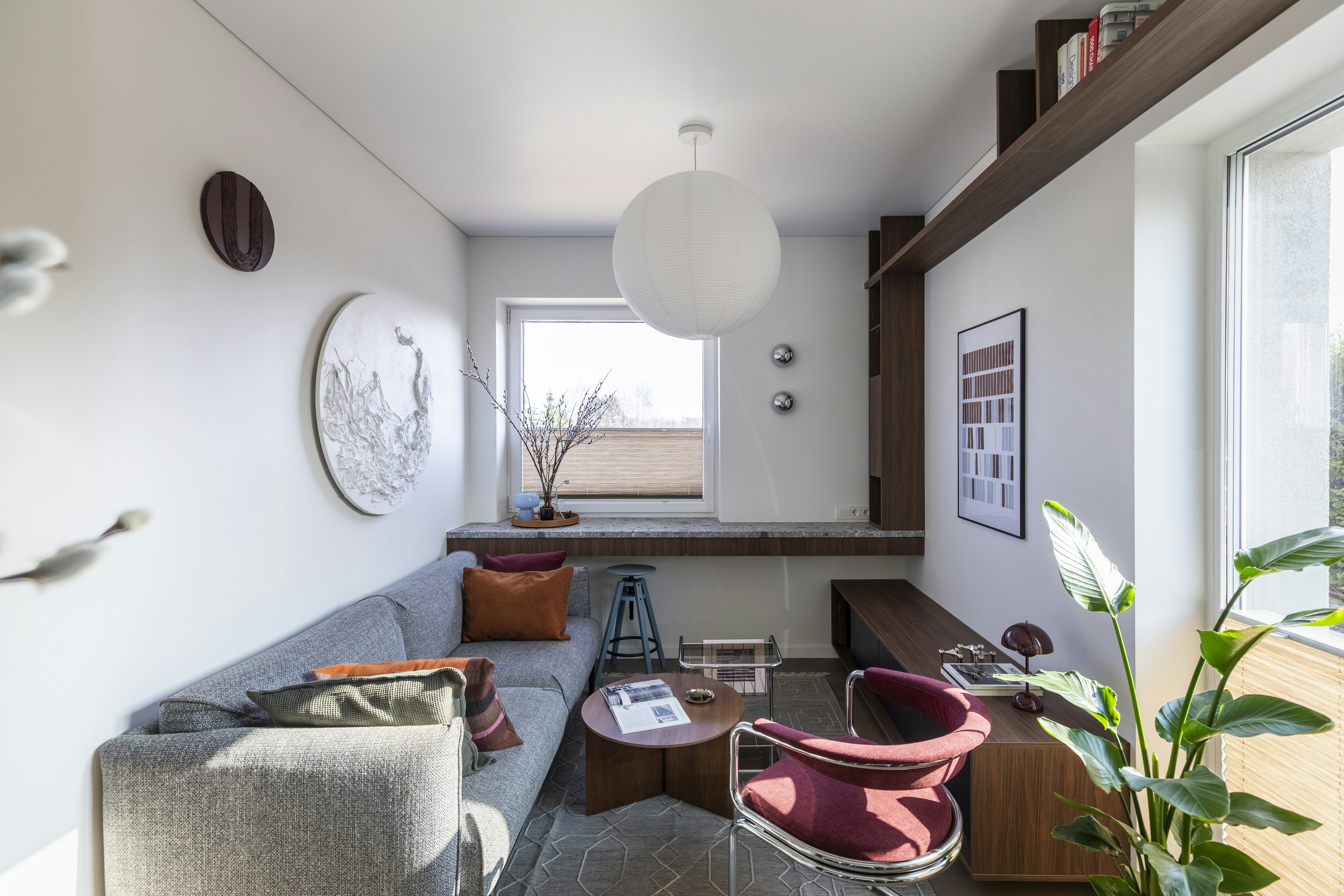 compact multi-use living space with gray sofa, wooden built-in shelving, and a desk in a small room
