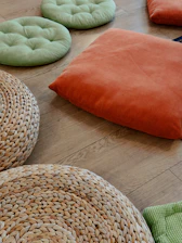 Colorful cushions and woven poufs arranged on a wooden floor.