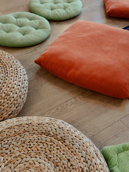 Colorful cushions and woven poufs arranged on a wooden floor.