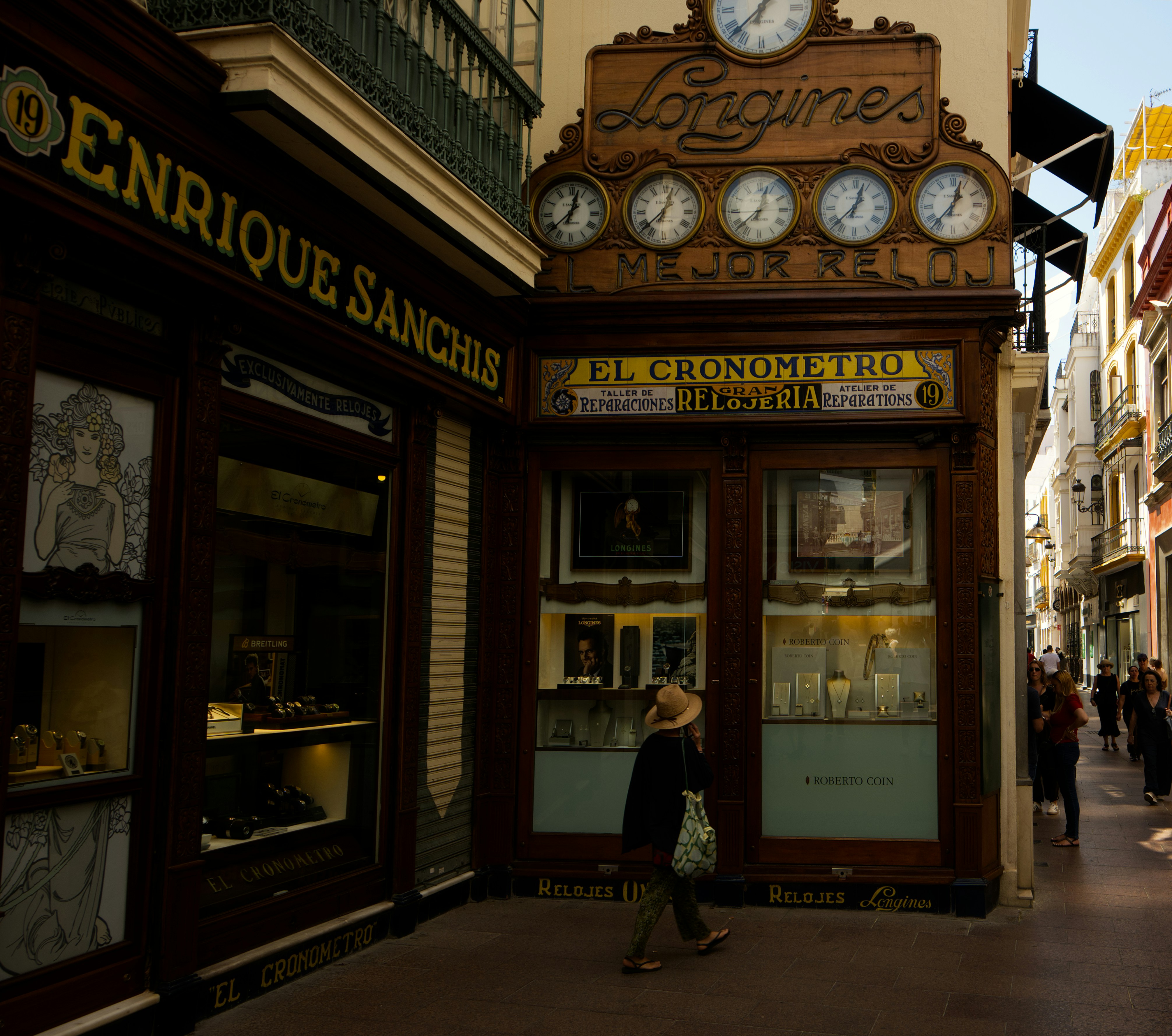 Historic storefronts with longines clocks and a person walking.