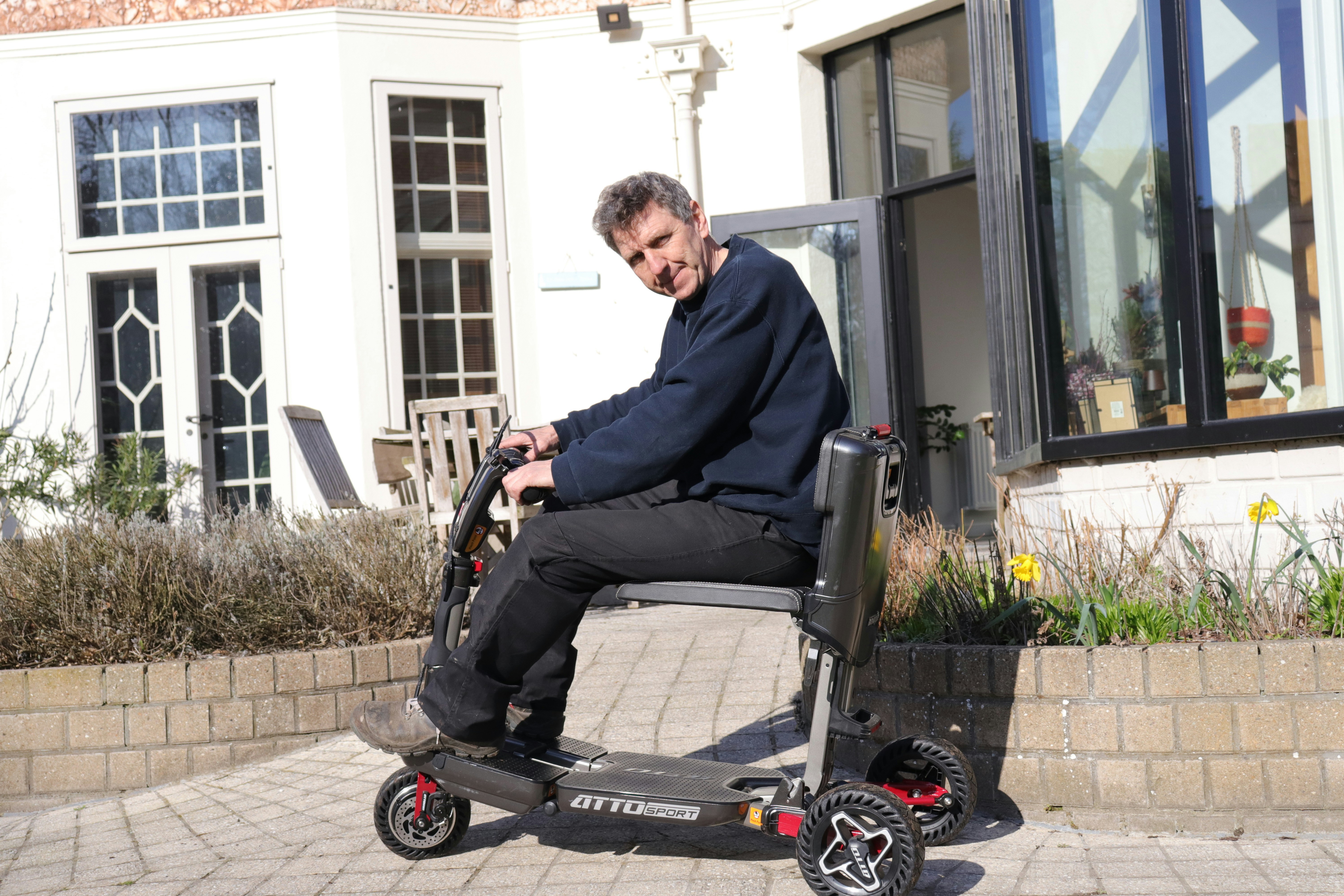 Man on mobility scooter in front of a house