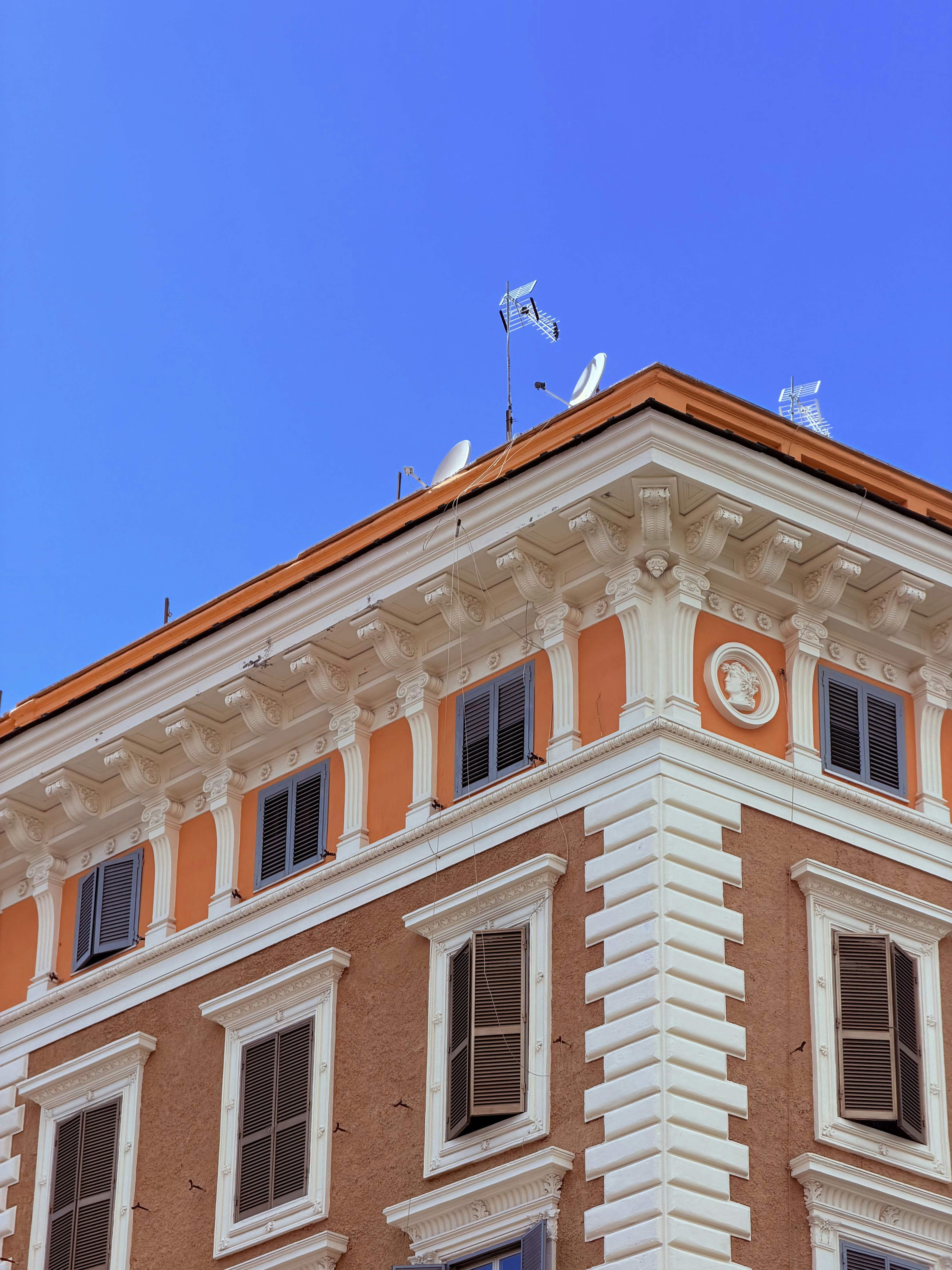 Ornate orange building corner with white details against blue sky.