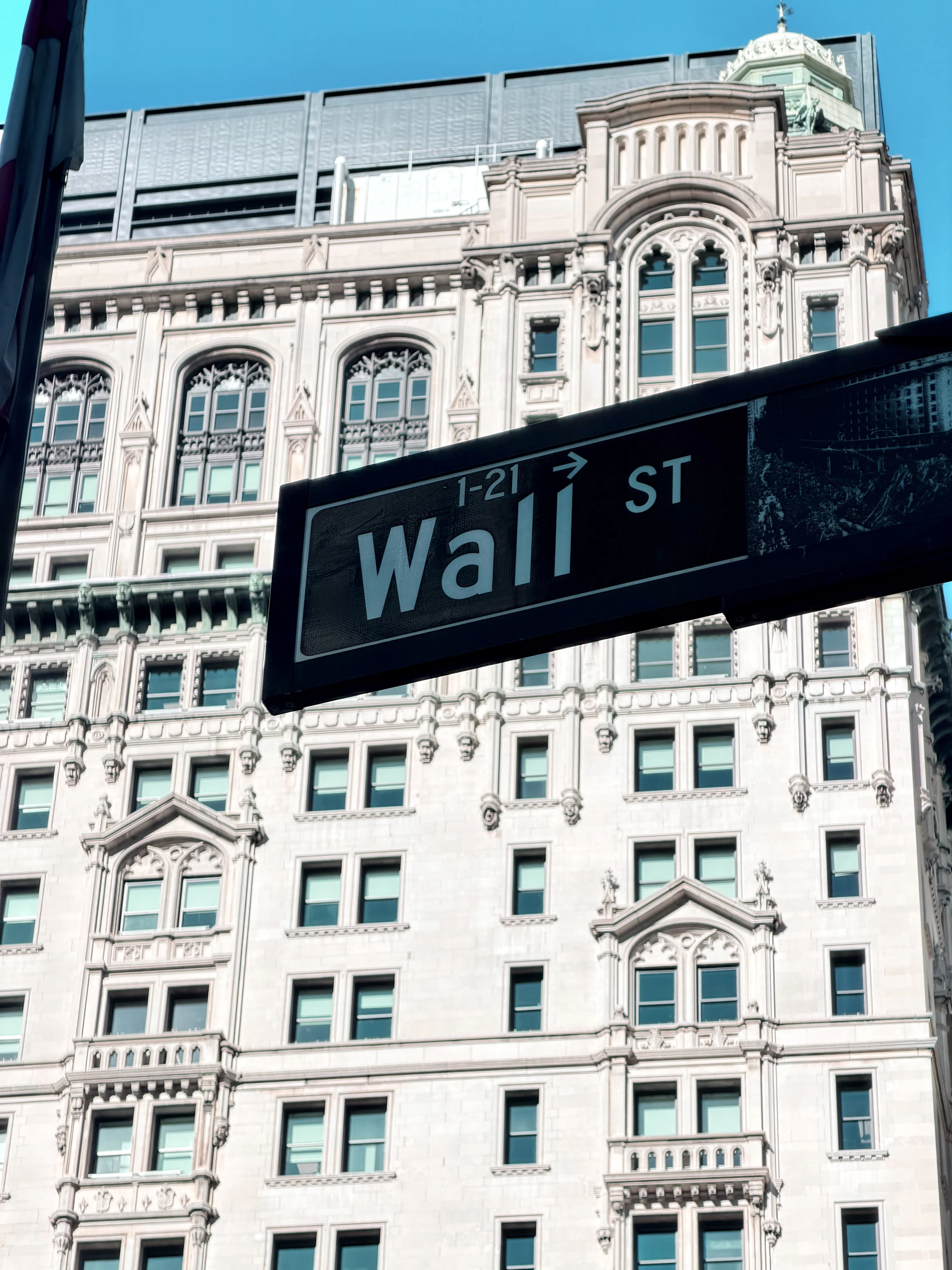 A Wall St street sign in front of a historic New York building