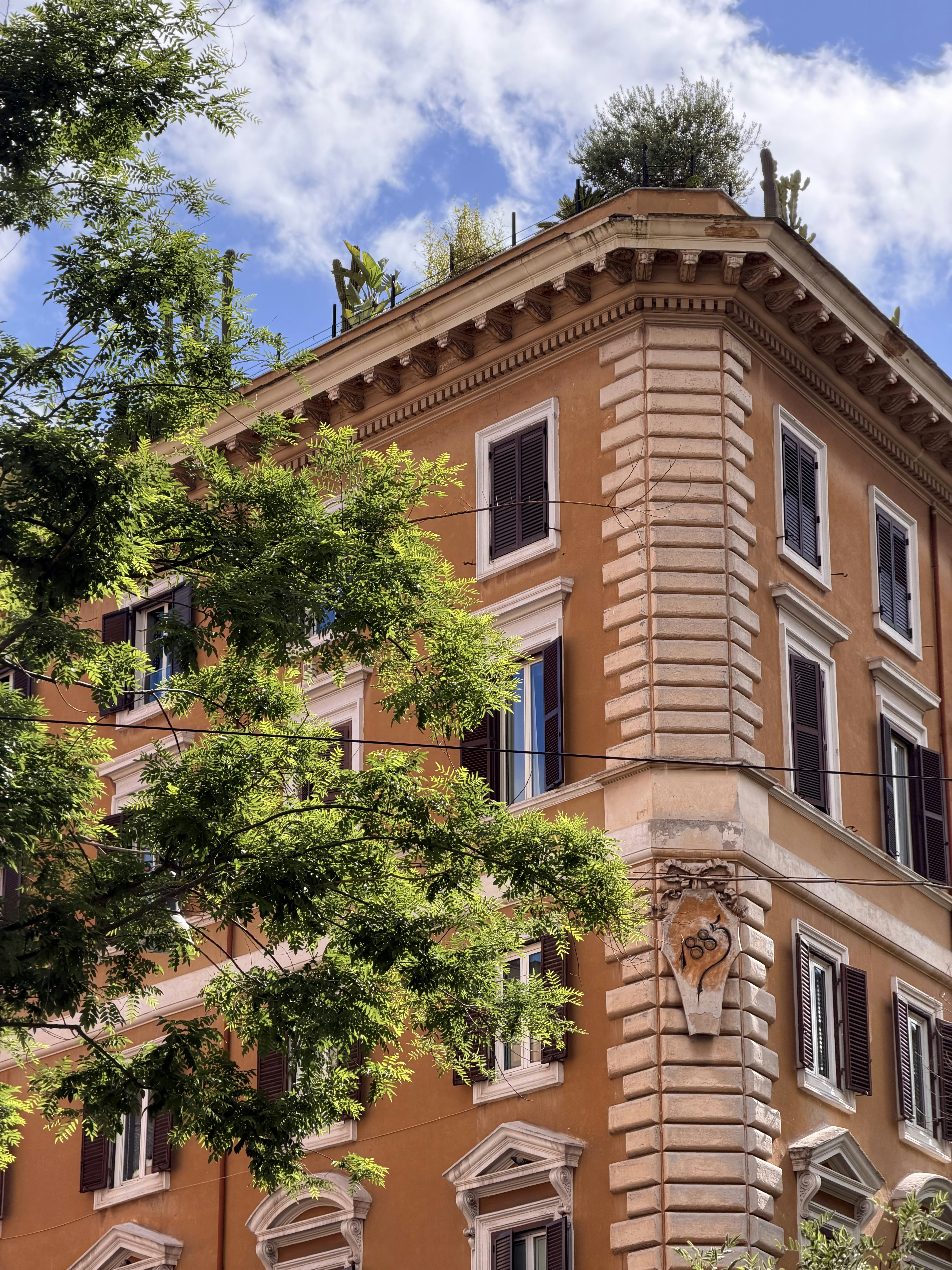 An orange building with green trees against a blue sky.