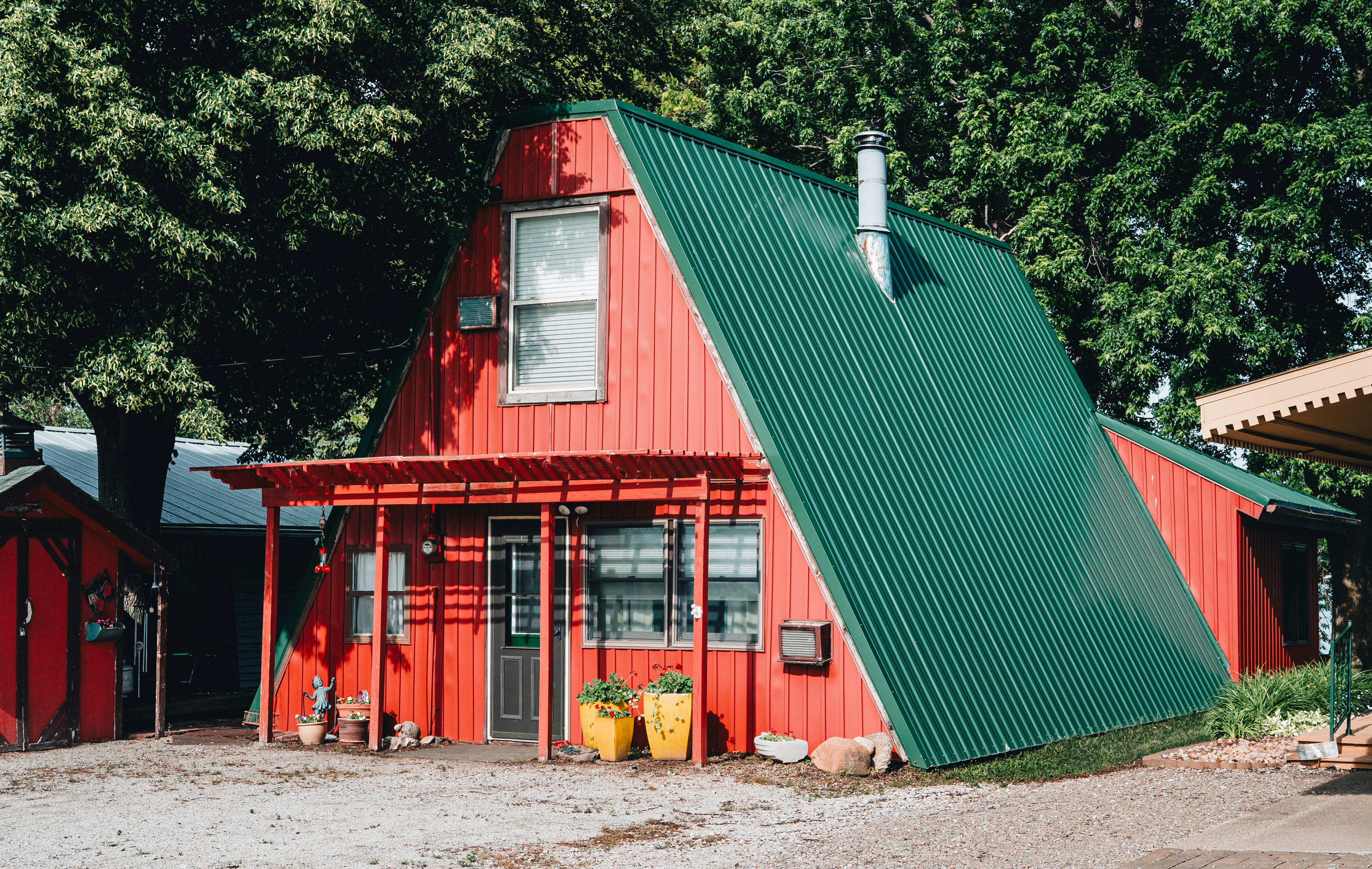 A vibrant red a-frame house with a green metal roof.