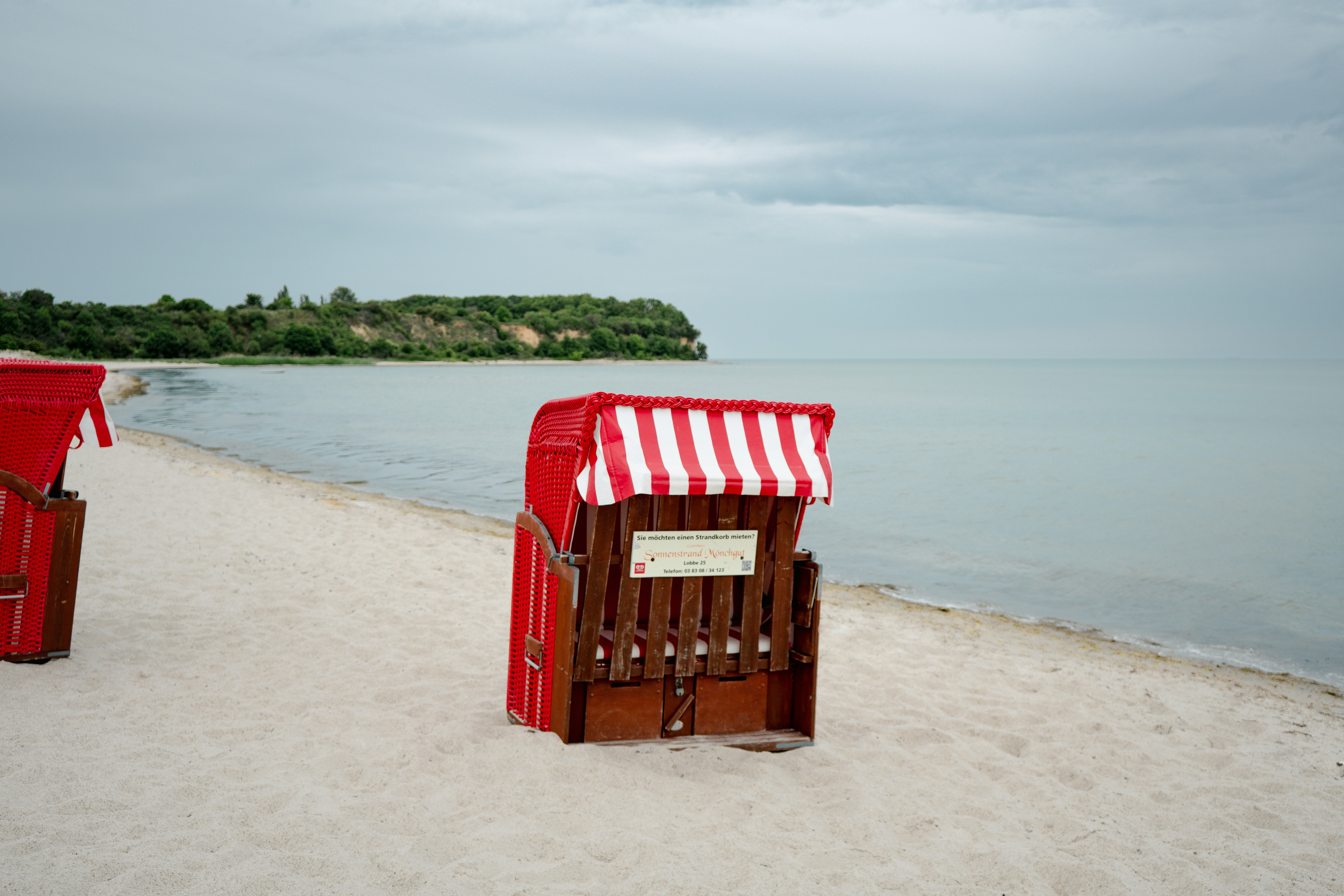 Des chaises longues rayées de rouge sur une plage de sable.