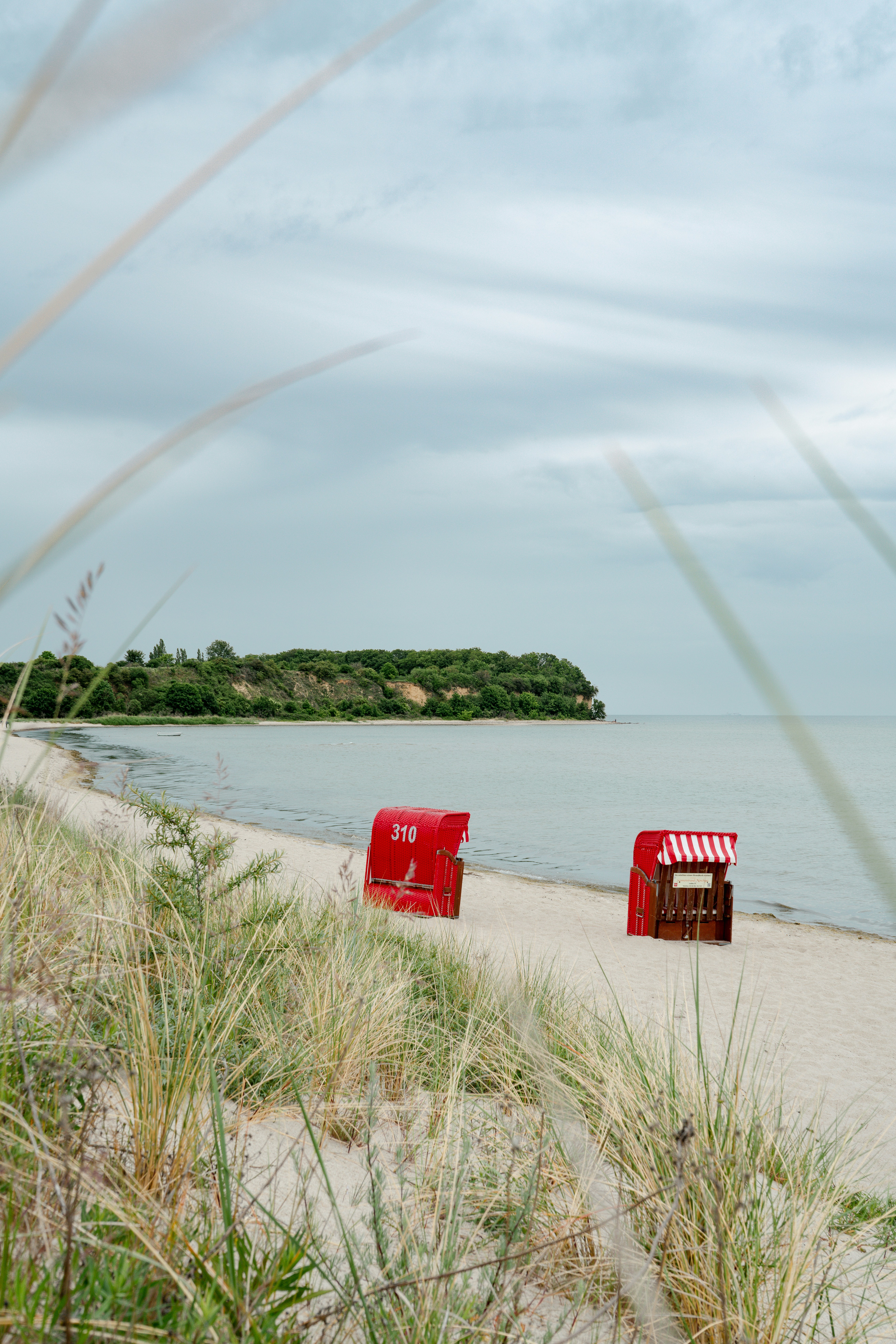 Deux chaises longues rouges sur une plage de sable paisible.