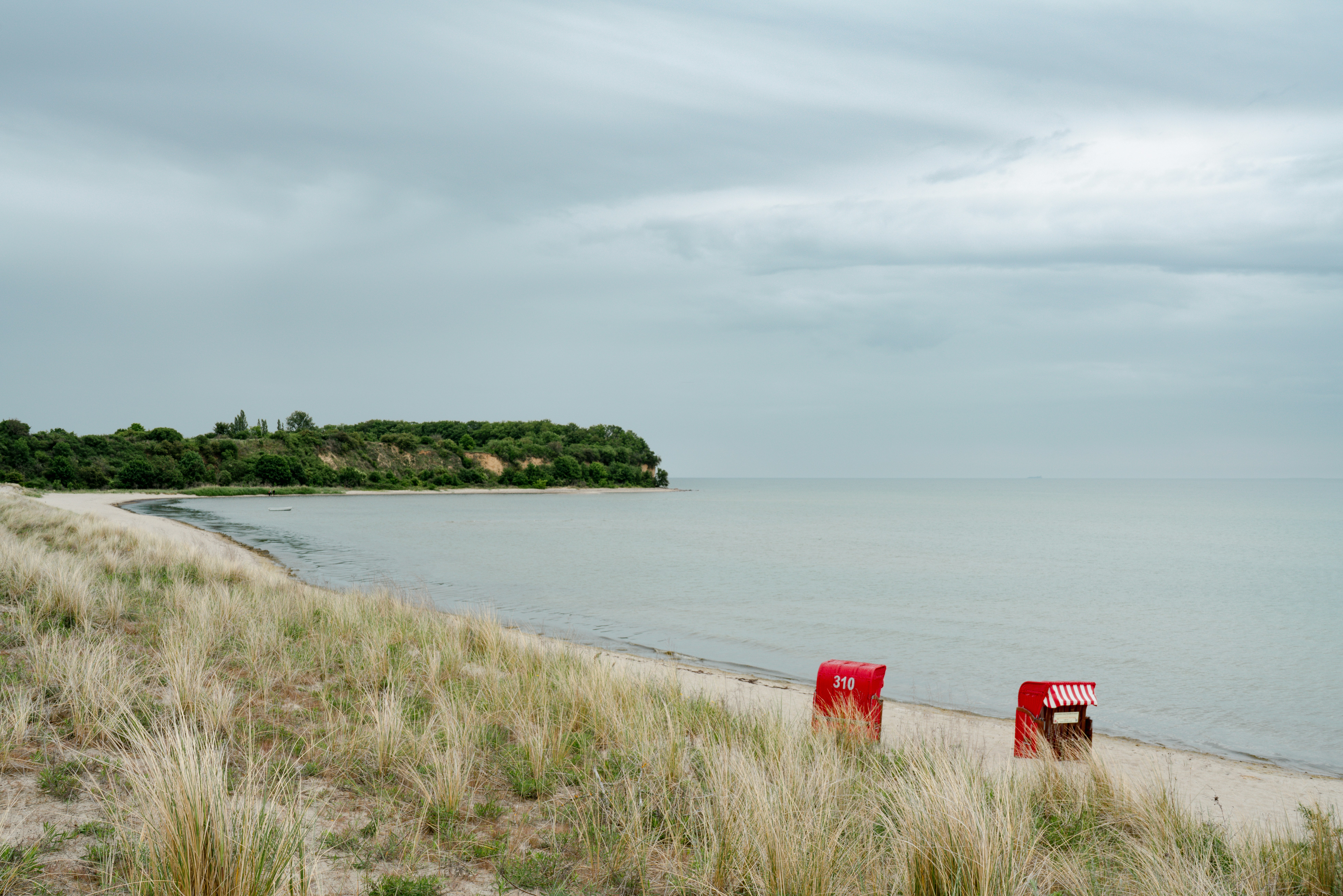 Deux chaises longues rouges sur une plage de sable avec l’océan.