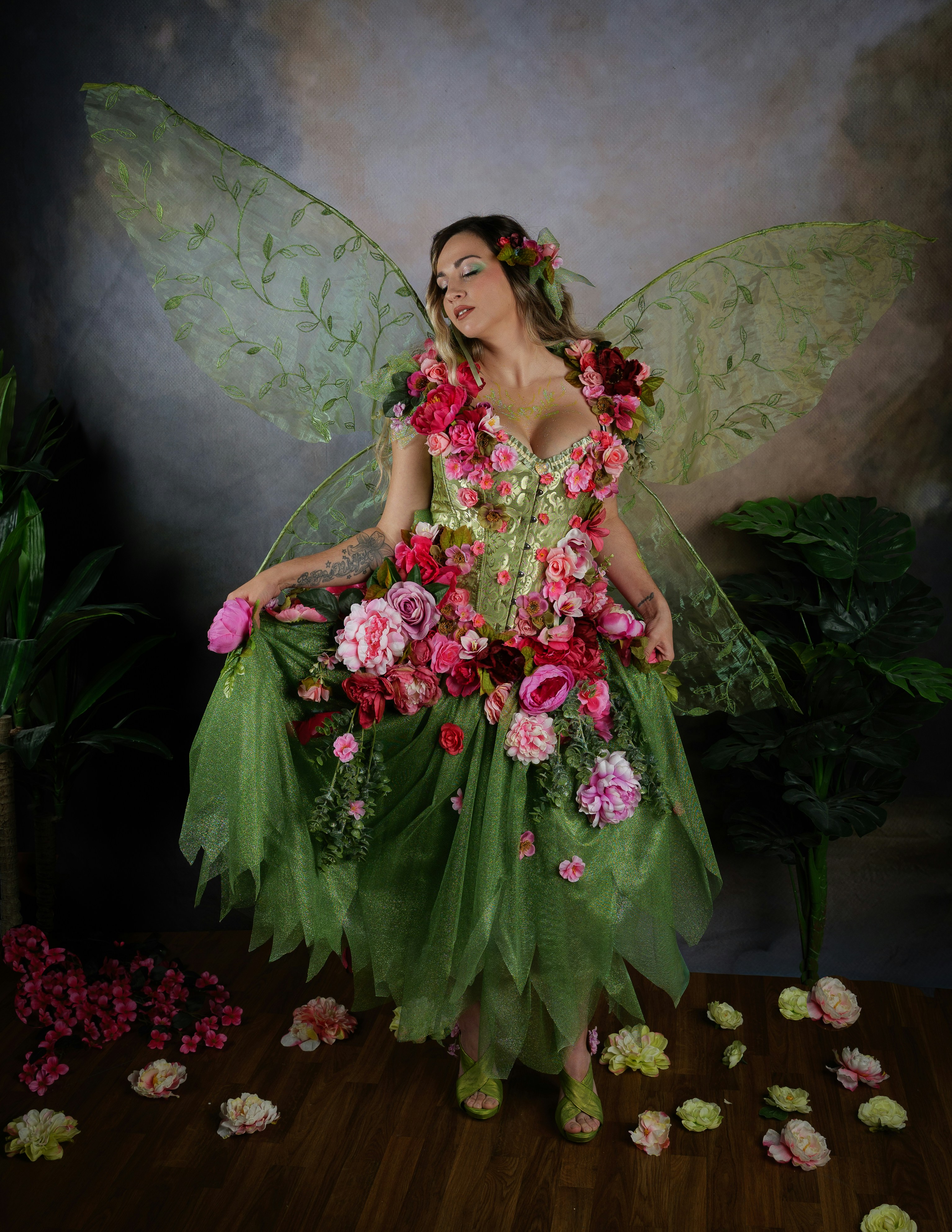 Mujer con un vestido de hada floral con alas verdes.