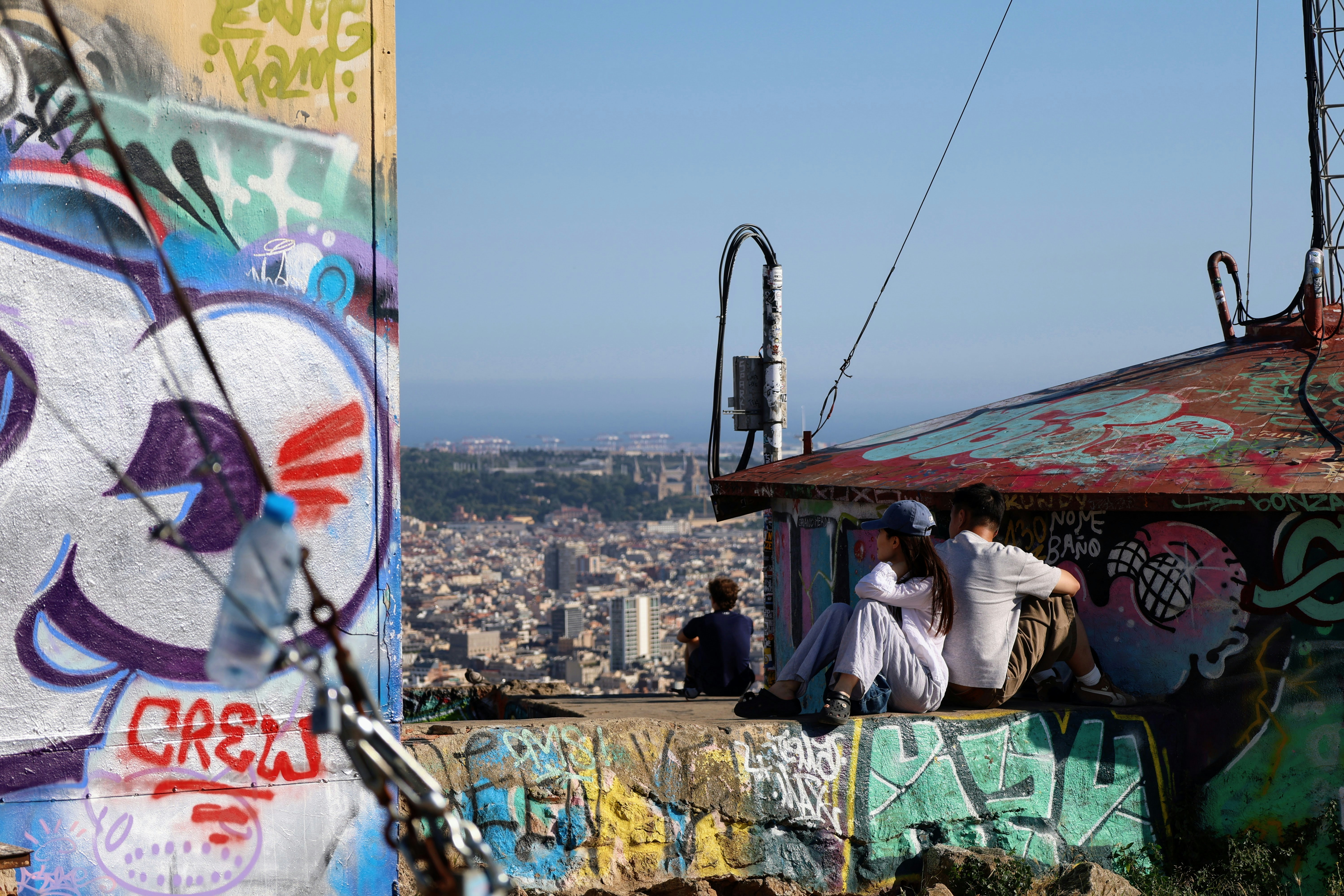 People sitting on a graffiti-covered rooftop overlooking a city.