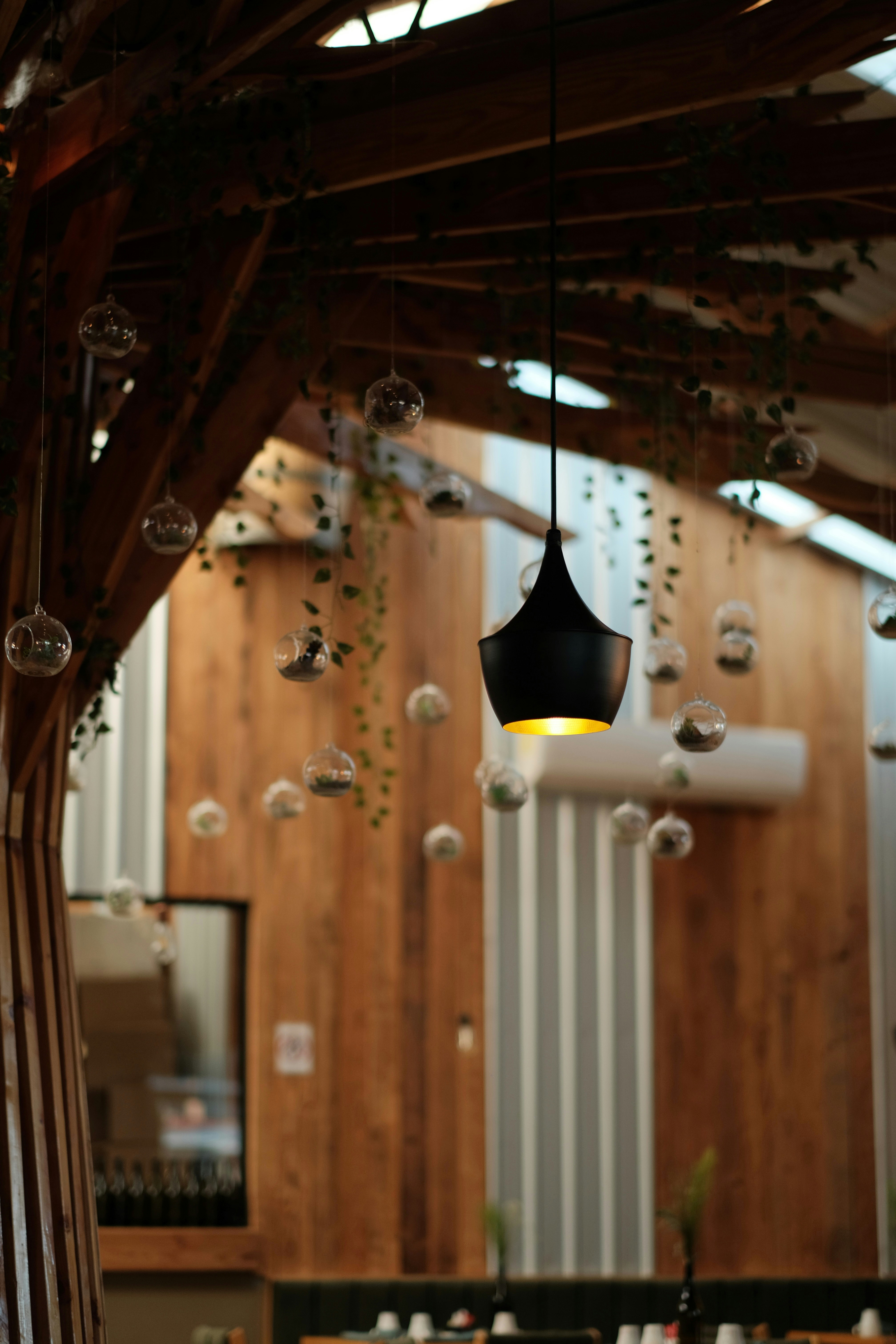A cozy rustic café interior with hanging warm lightbulbs and elegant wooden tables.