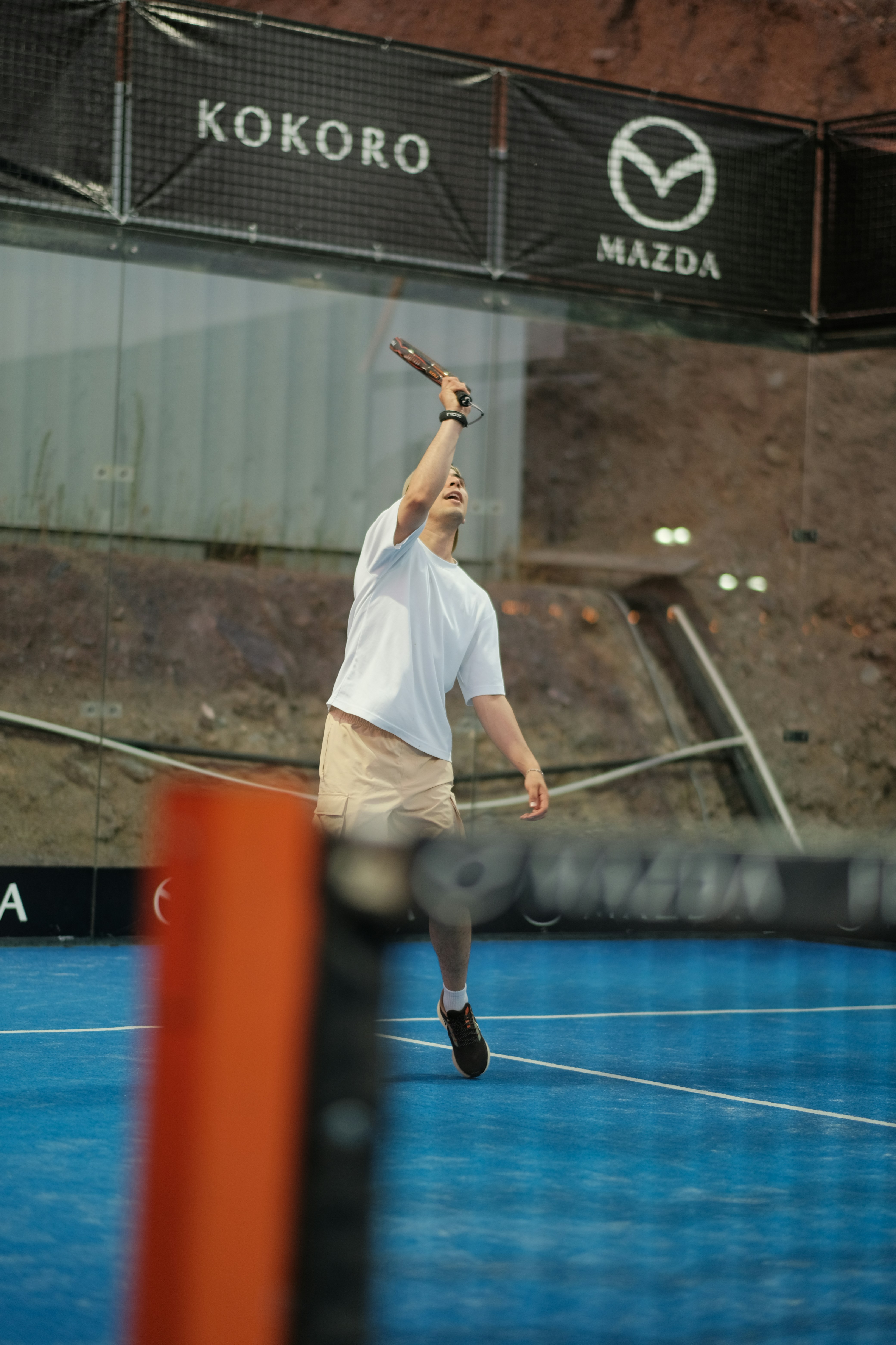 Ein Mann in Weiß spielt Padel auf einem blauen Platz.
