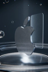 A clear glass apple logo on a reflective dark surface
