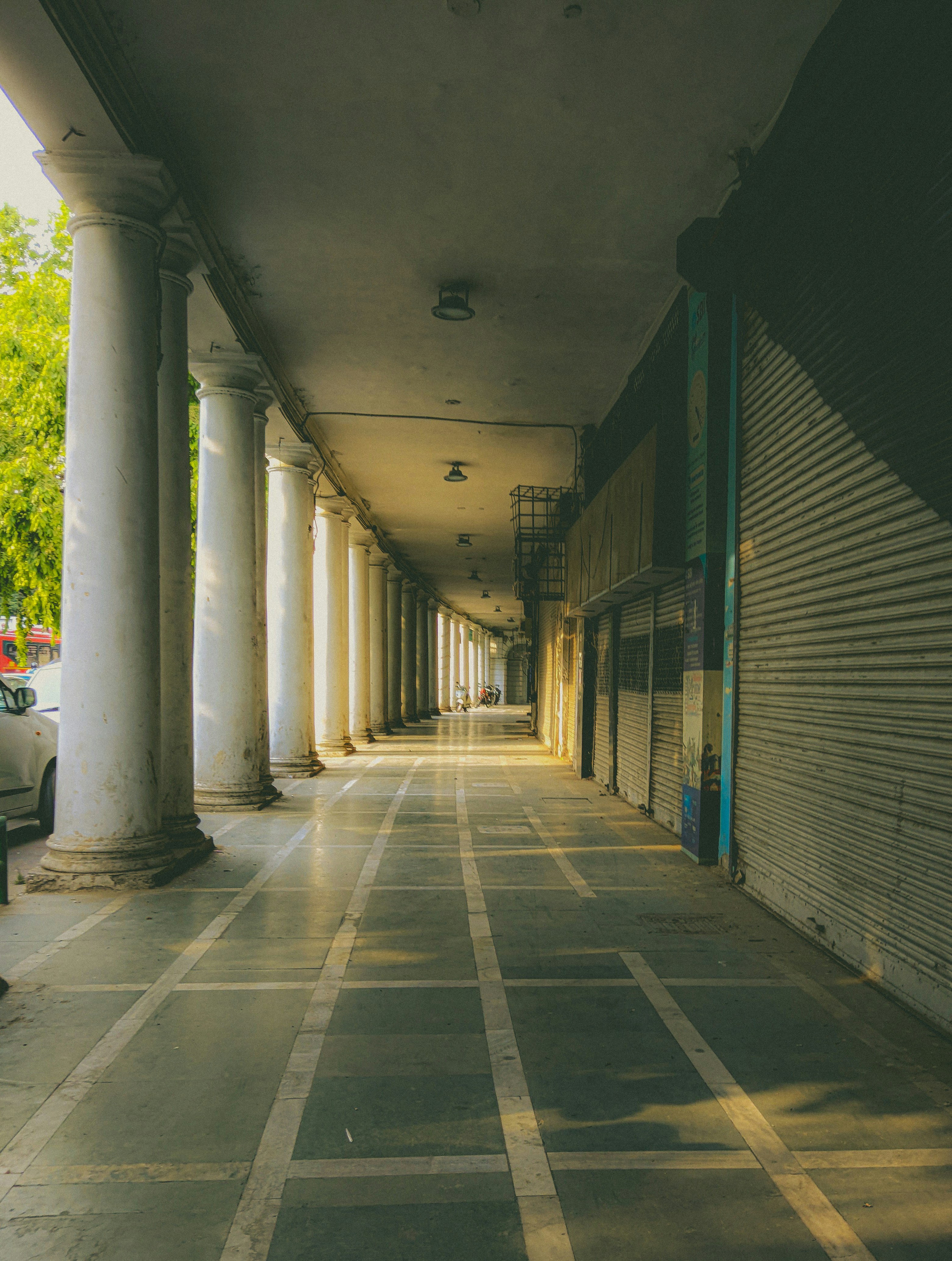 A long colonnade with pillars and closed shops.