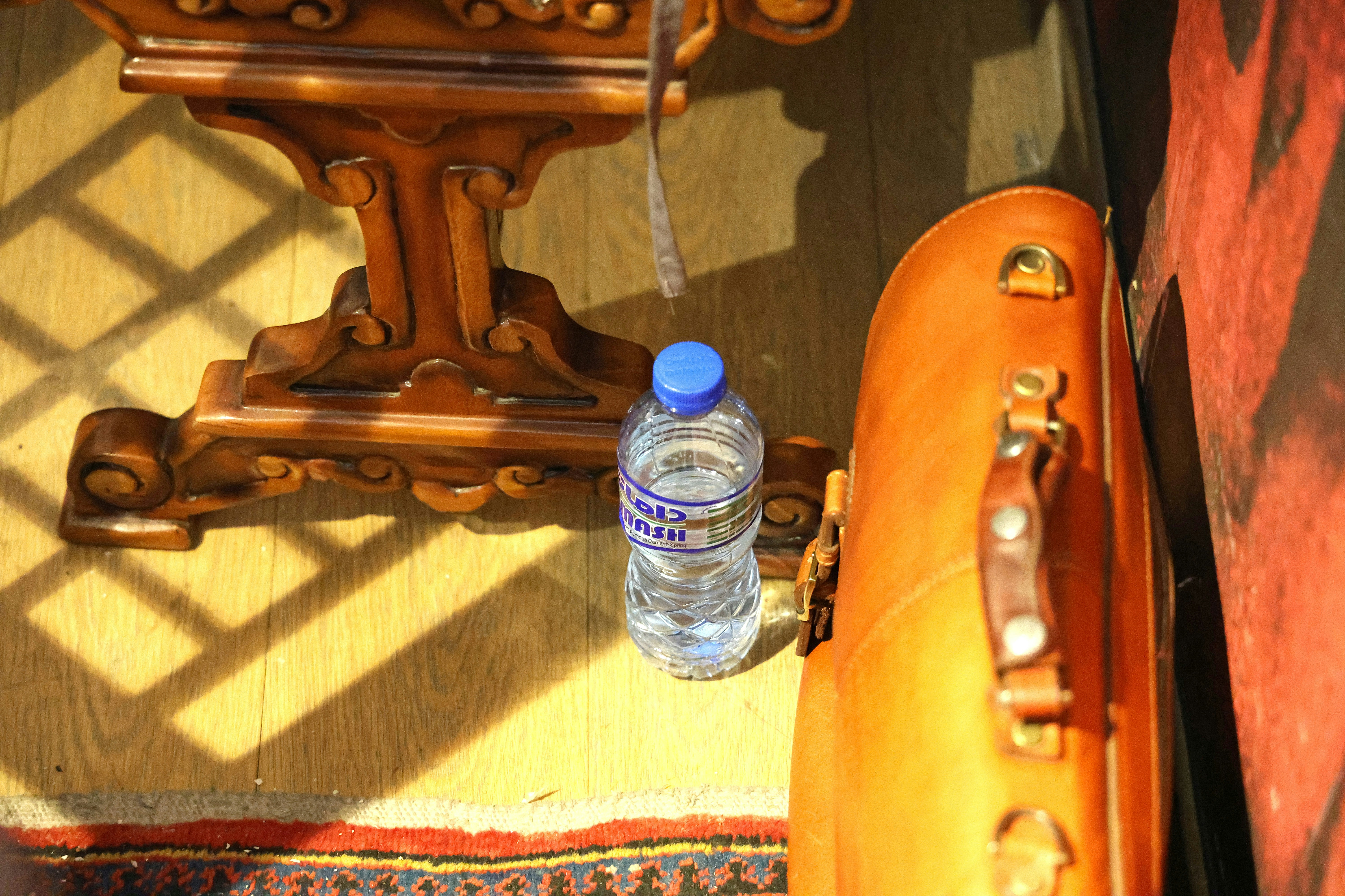 Botol air plastik, koper coklat, dan meja kayu berhias.