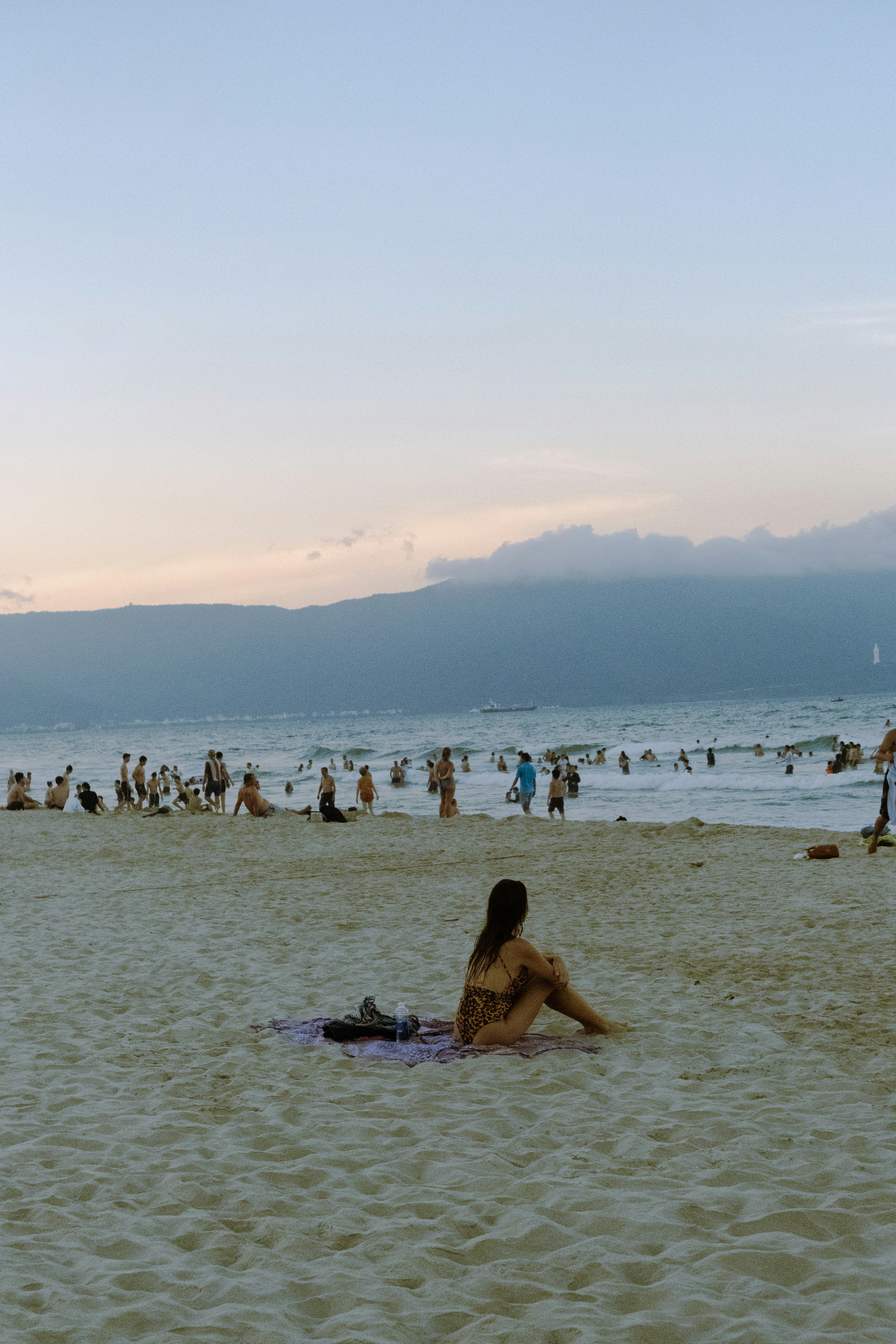 Woman relaxes on a crowded beach at sunset