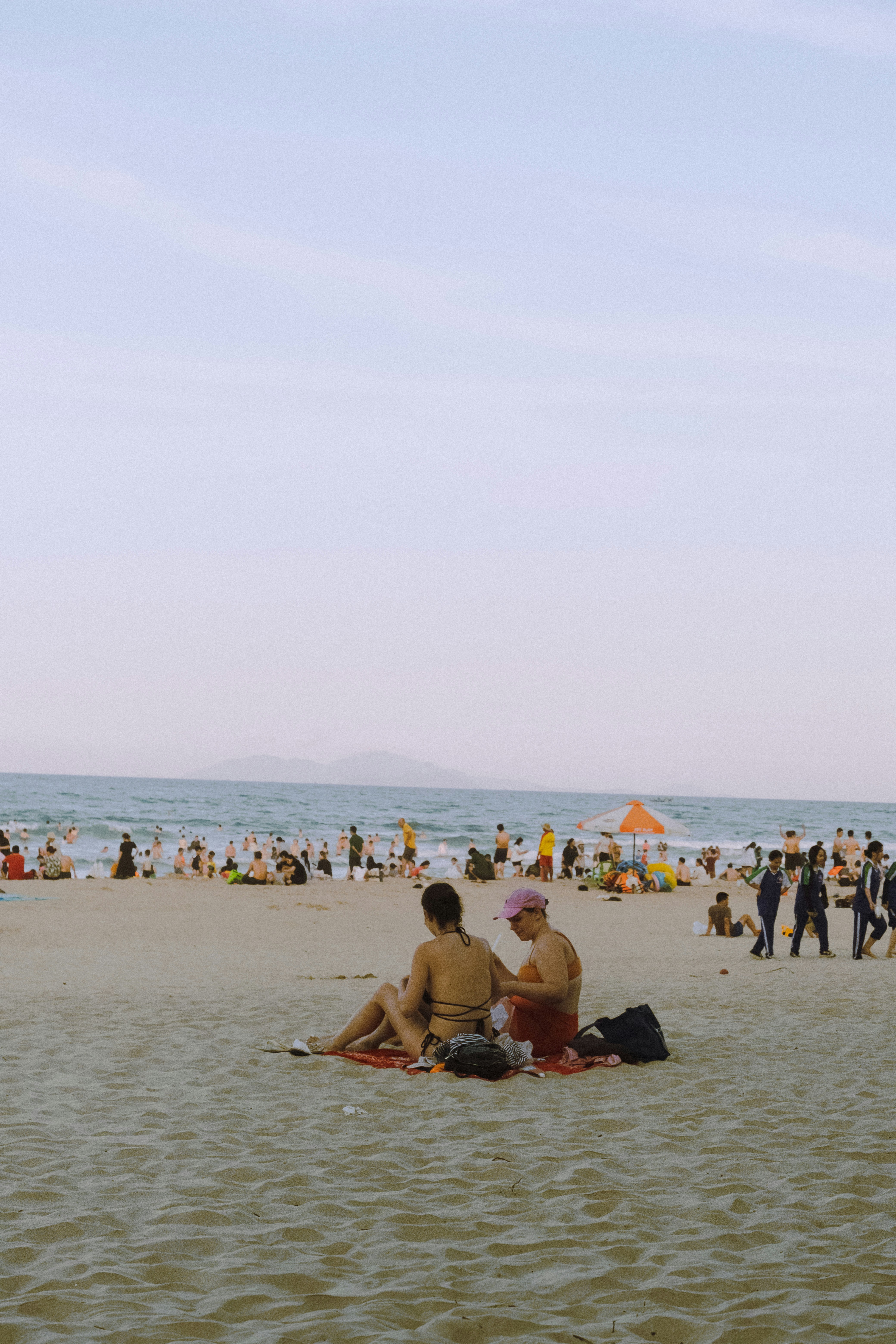 Two people relaxing on a crowded beach by the ocean