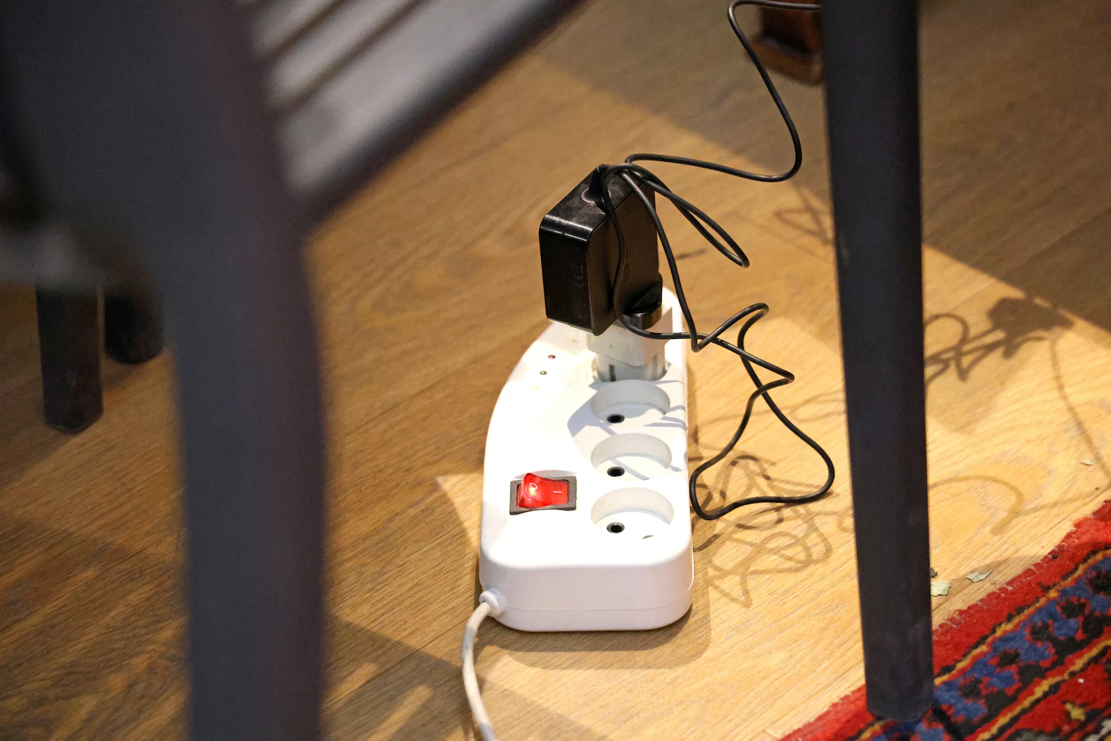 A power strip with a plugged-in adapter on a wooden floor