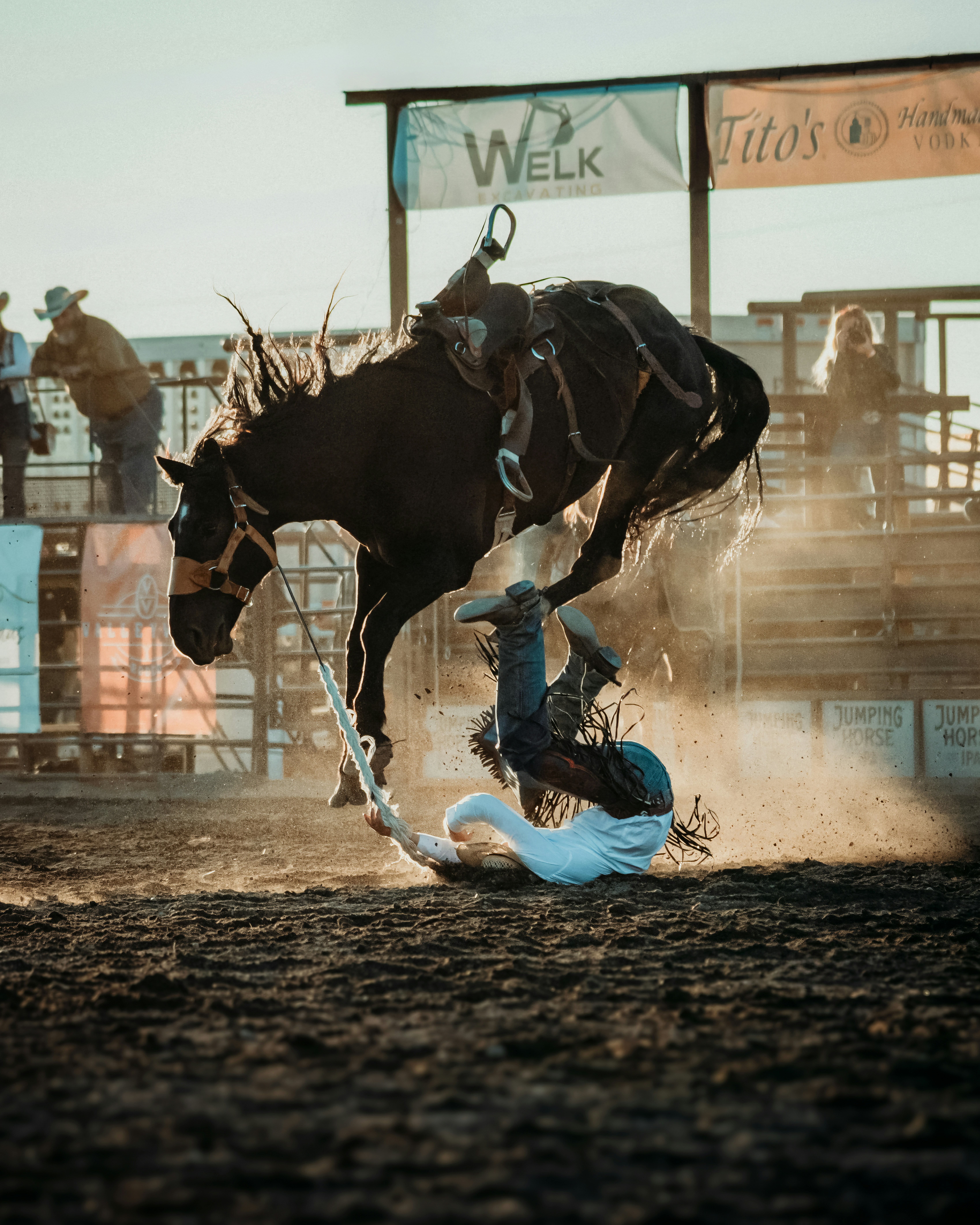 Cowboy falling off a bucking horse during a rodeo event.