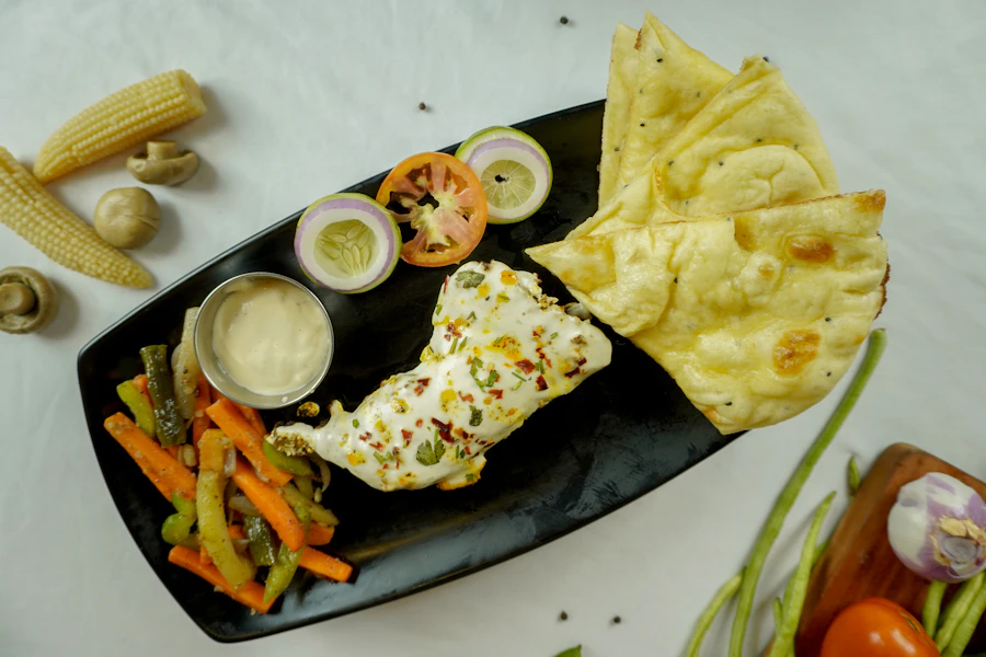 A plate of paneer with naan bread, vegetables and sauce