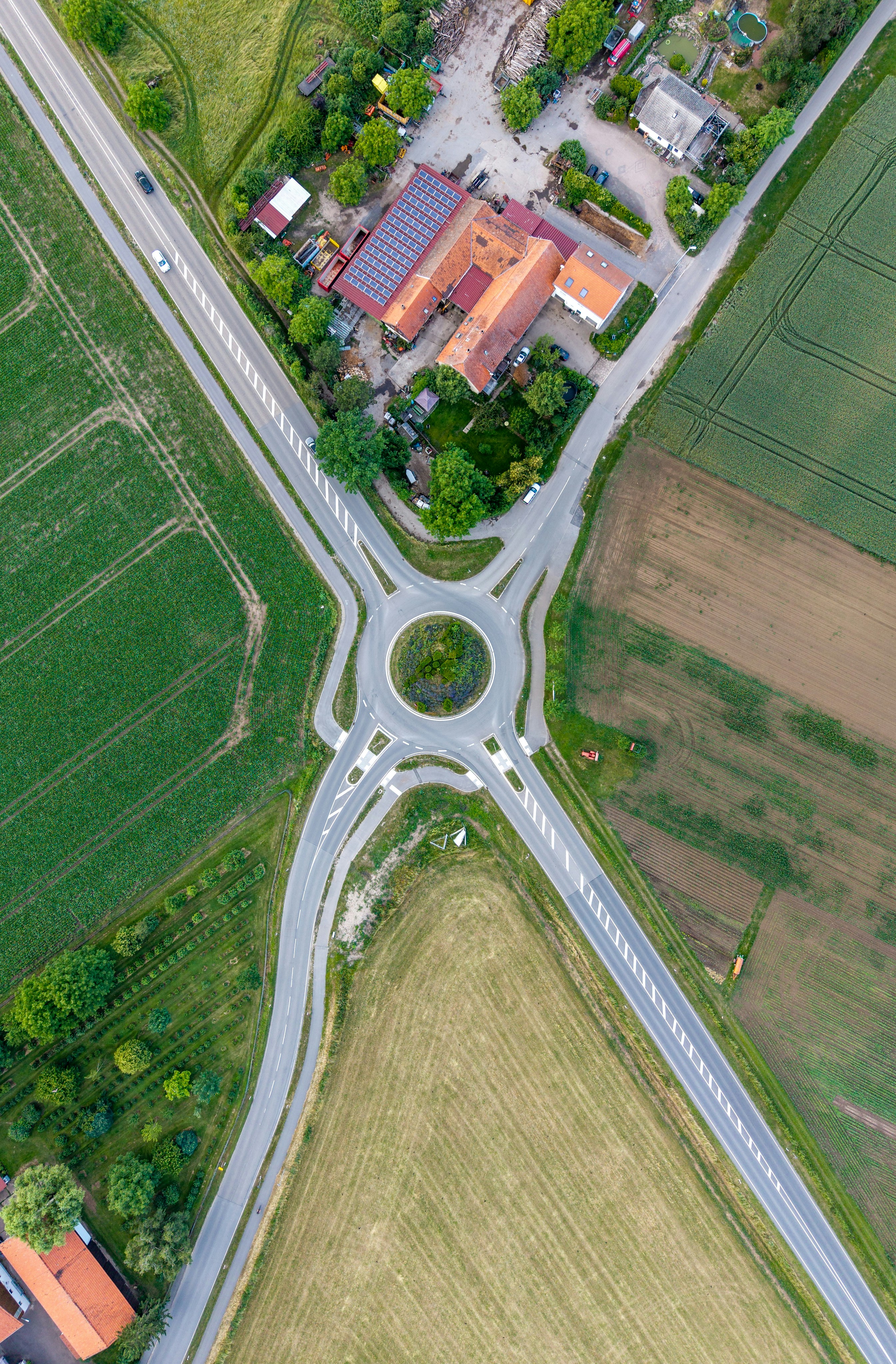 Rotonda rurale tra campi verdi e edifici di villaggio.