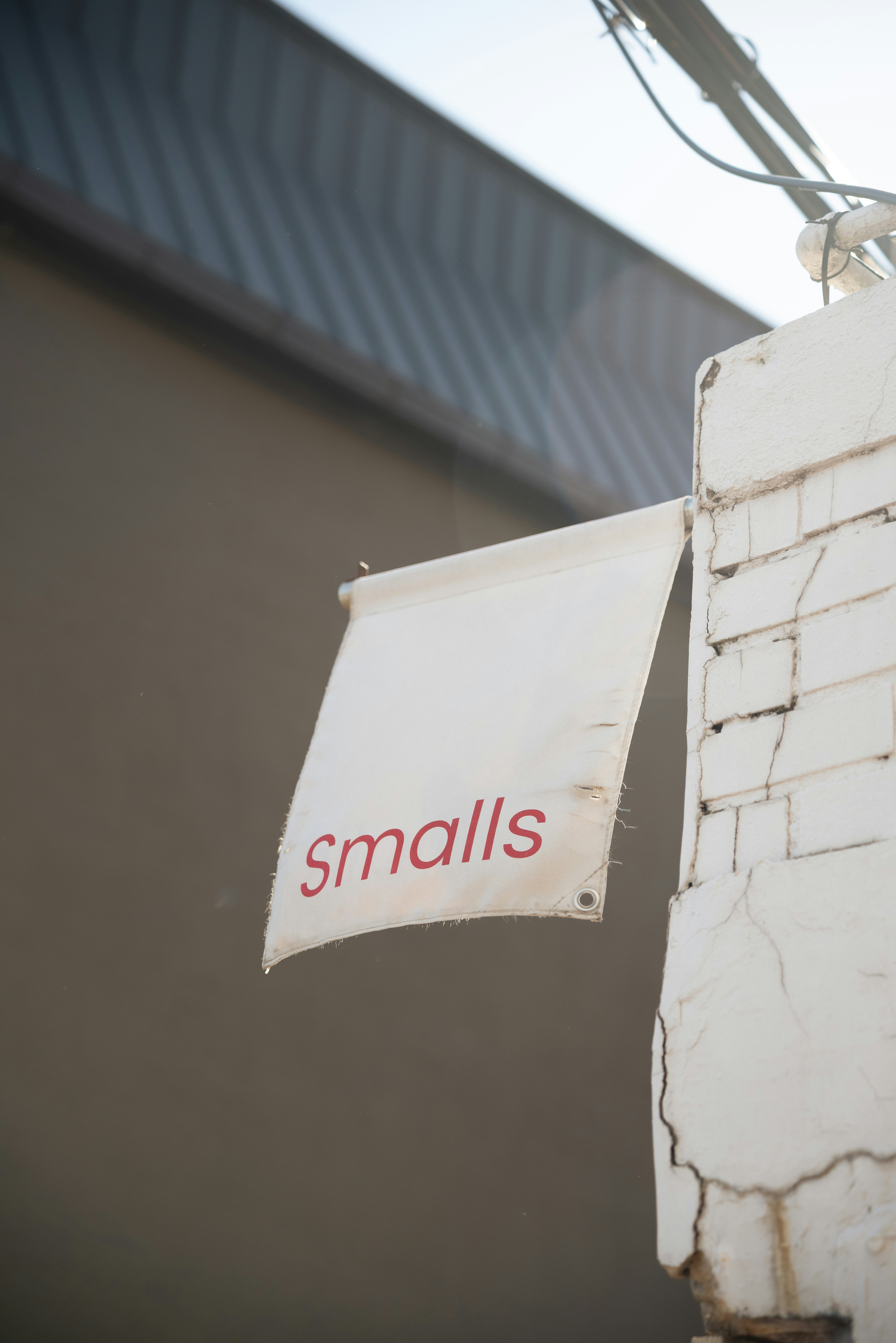 A white "smalls" sign hangs from a brick pillar.